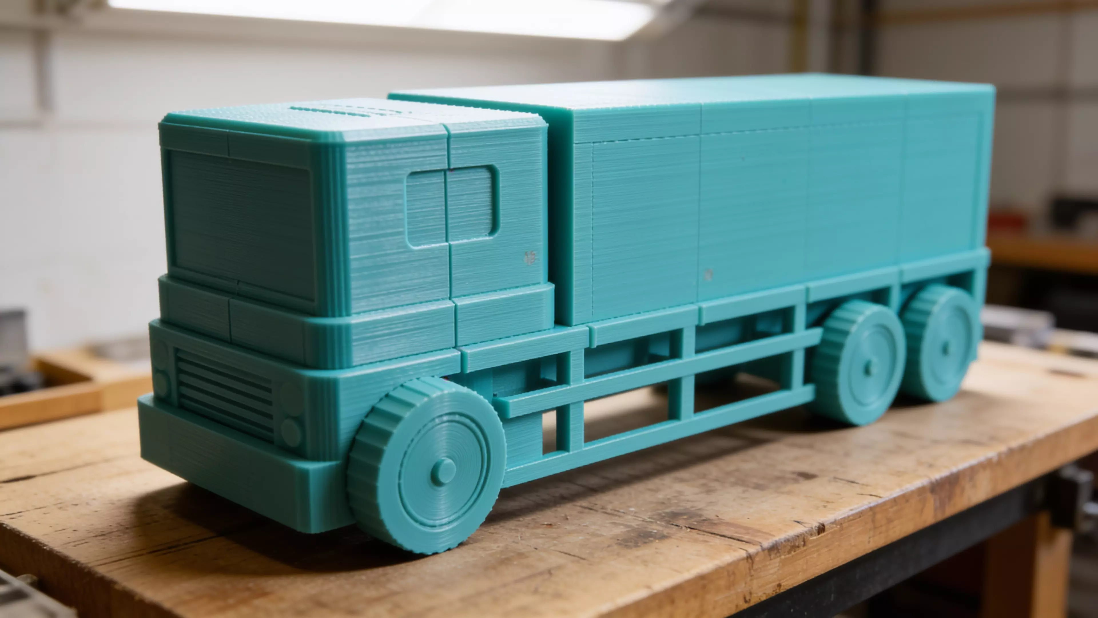 Design a unique, cute, vibrant futuristic truck-shaped display shelf for four DGX Spark units. The design should look like a real miniature autonomous delivery truck, where the cargo body is integrated into the truck and functions as an open display shelf.

DGX Spark dimensions:
150 mm L × 150…