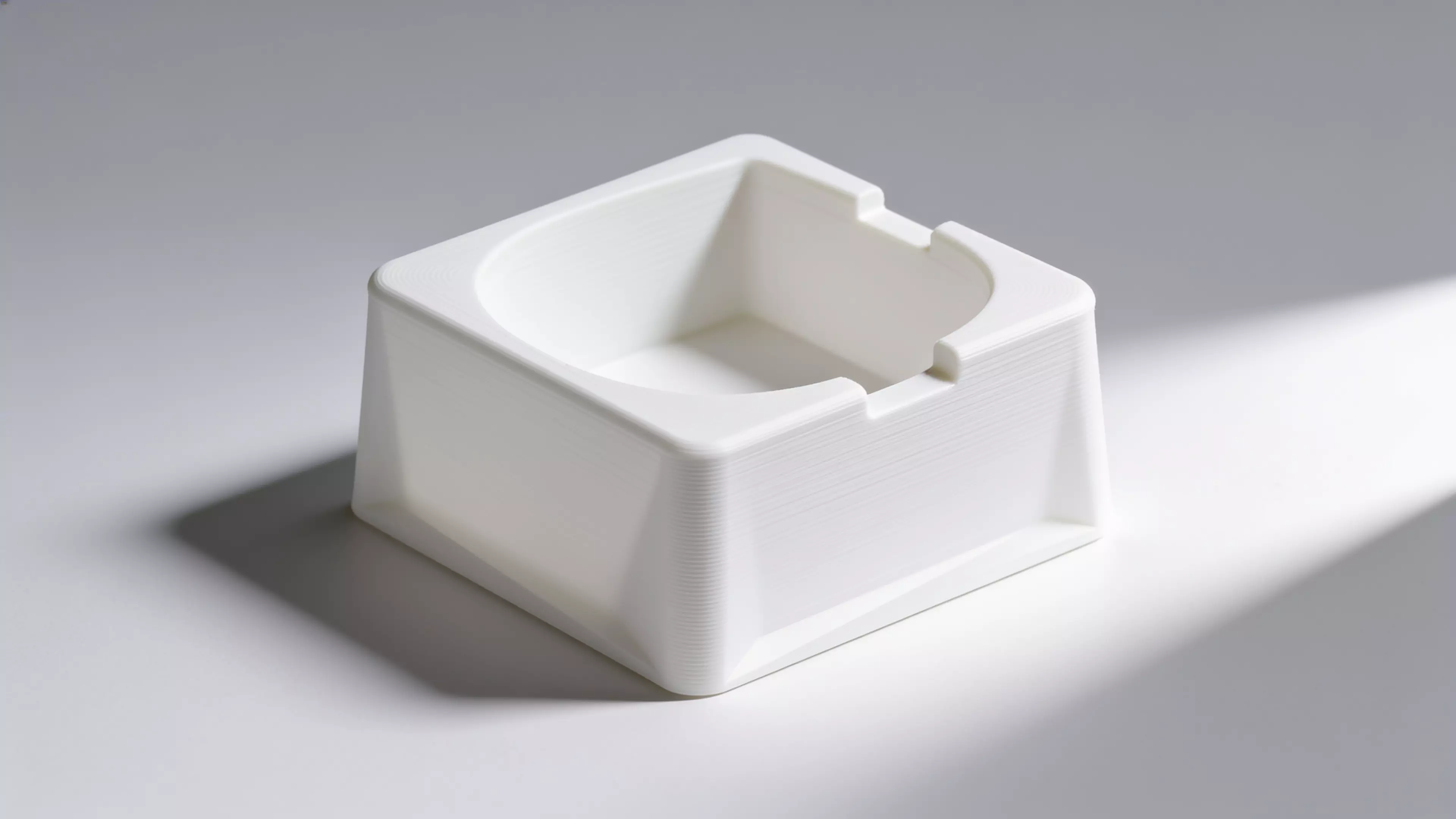 A single-piece, Scandinavian-minimal squircle stand (200 × 200 × 76 mm) that a standard 1-quart stainless bowl drops into from the top and hangs by its rolled rim on an internal support lip, with an anti-spill raised rim, two finger scallops for bowl removal, "NUNU" + paw icon raised on the front…