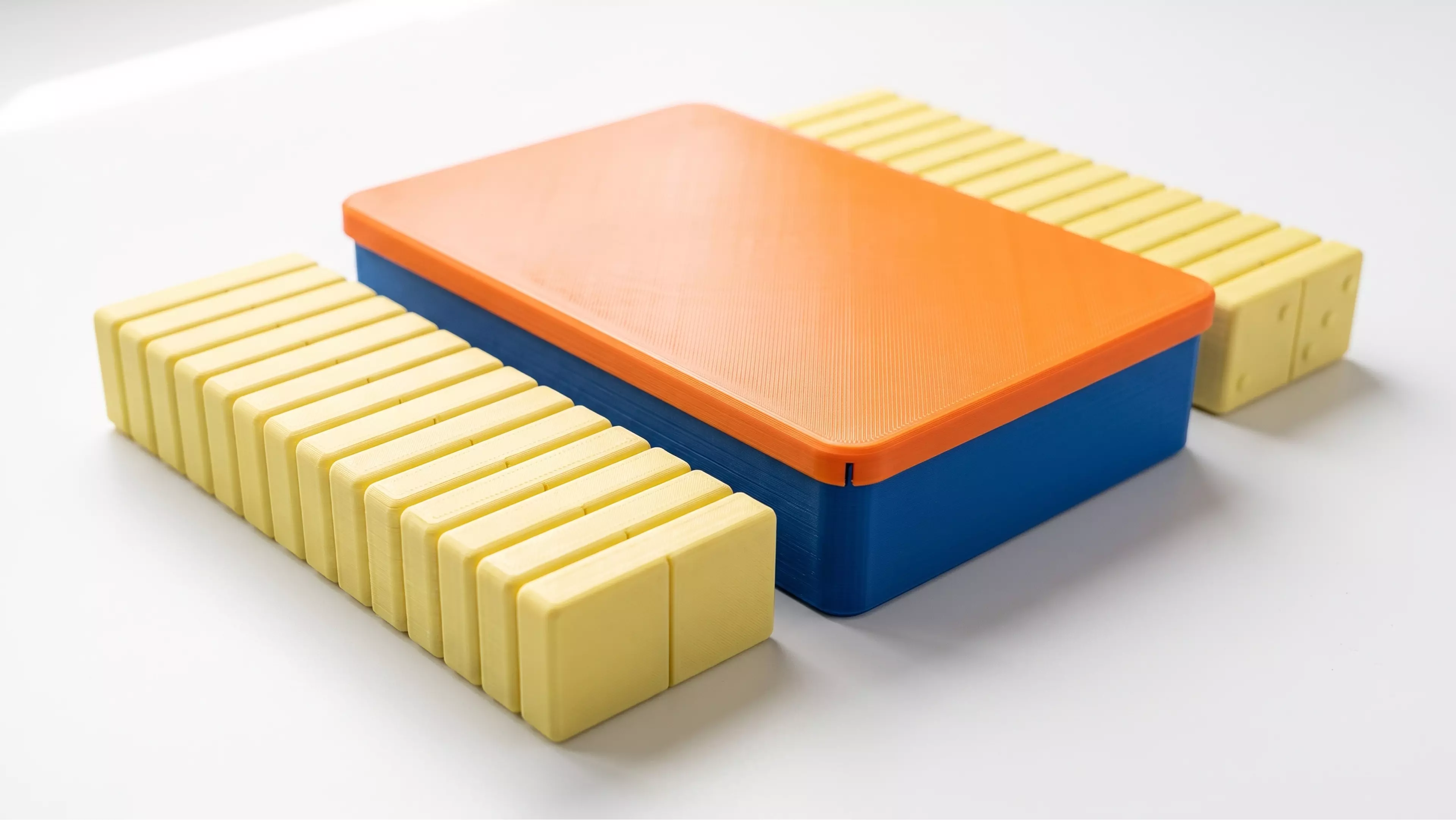 A complete Double-6 domino set — 28 tiles (48 x 24 x 8 mm) with raised embossed pips — stored in a fitted two-row tray with a slip-fit lid.