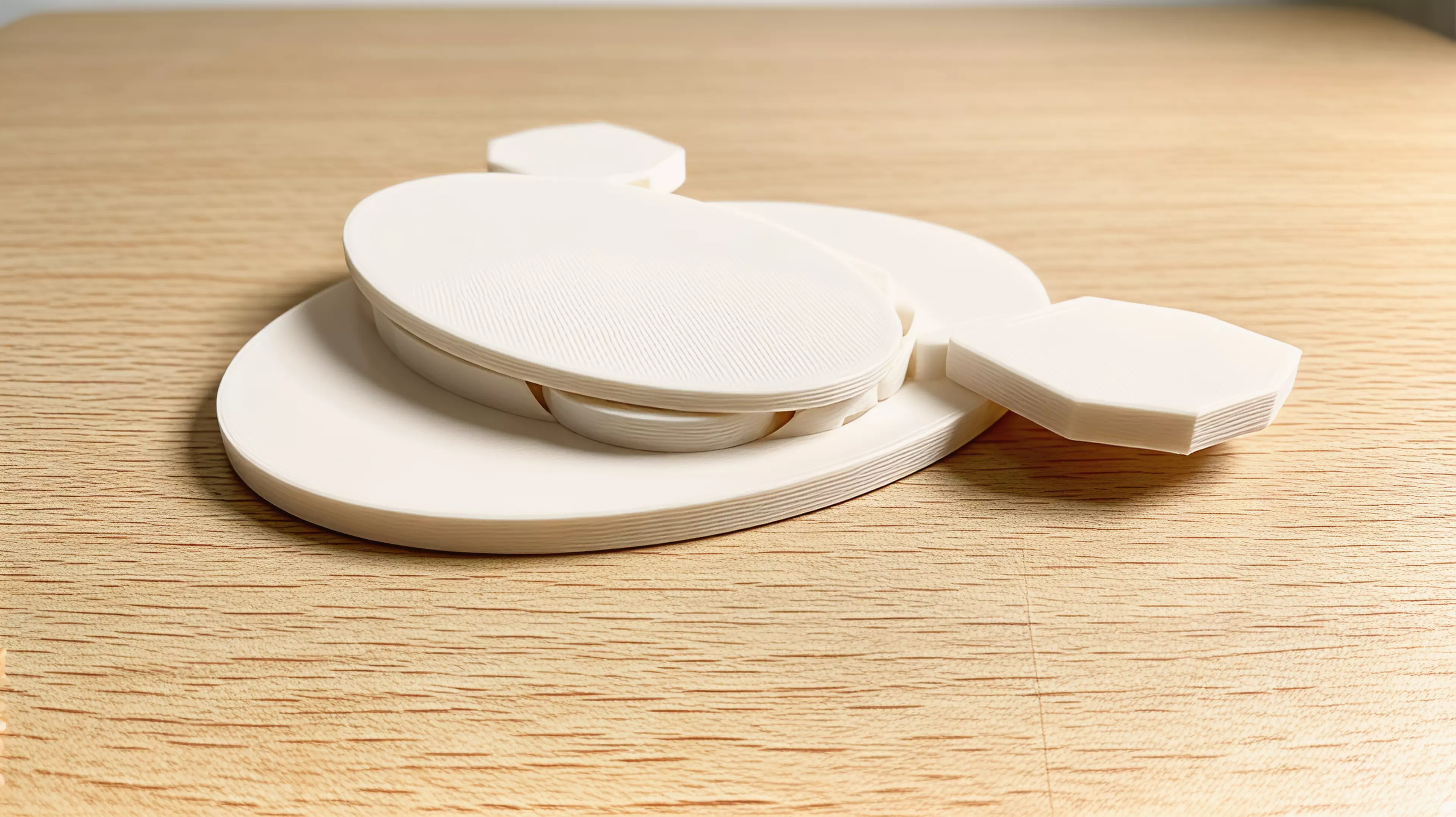A three-part, hardware-free hand-powered desk toy: sweeping the left wing rotates the meshed pair from a low crescent form toward a moth silhouette with six star apertures.
