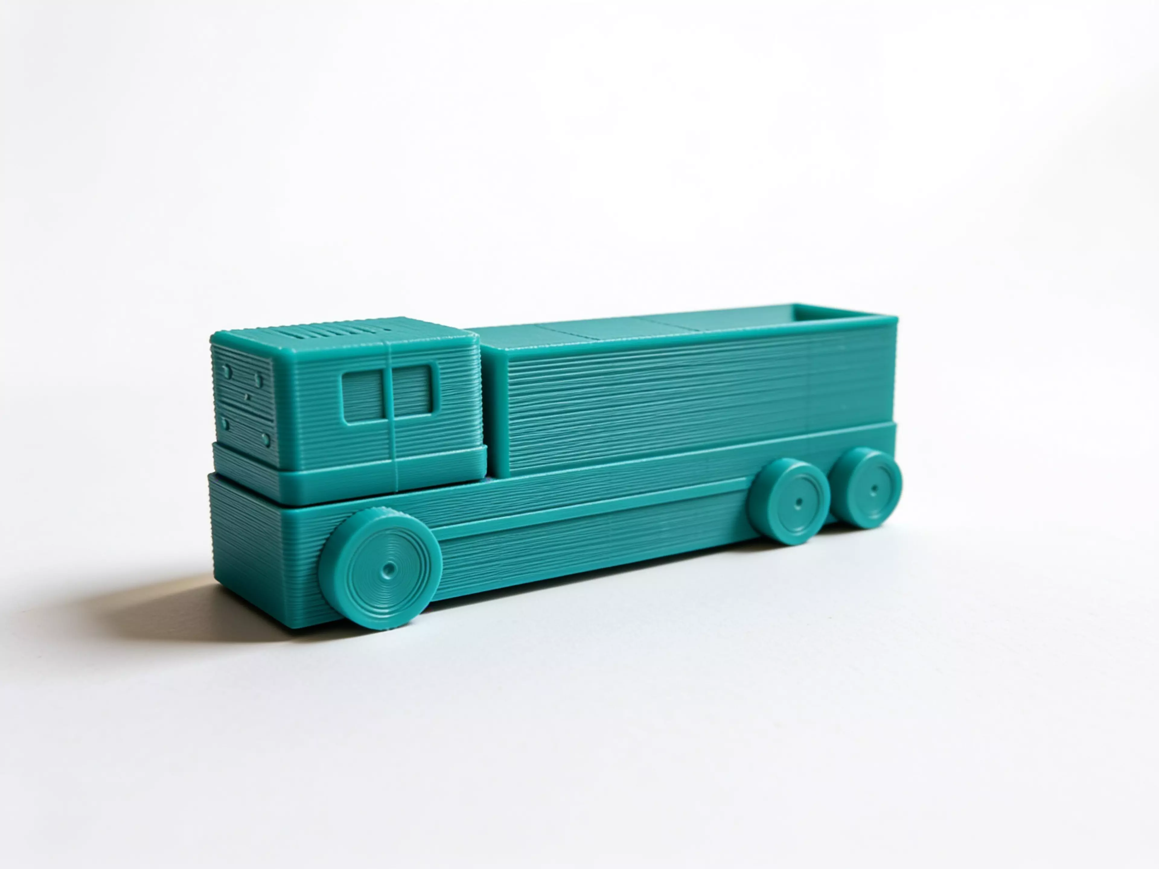 Design a unique, cute, vibrant futuristic truck-shaped display shelf for four DGX Spark units. The design should look like a real miniature autonomous delivery truck, where the cargo body is integrated into the truck and functions as an open display shelf.

DGX Spark dimensions:
150 mm L × 150…