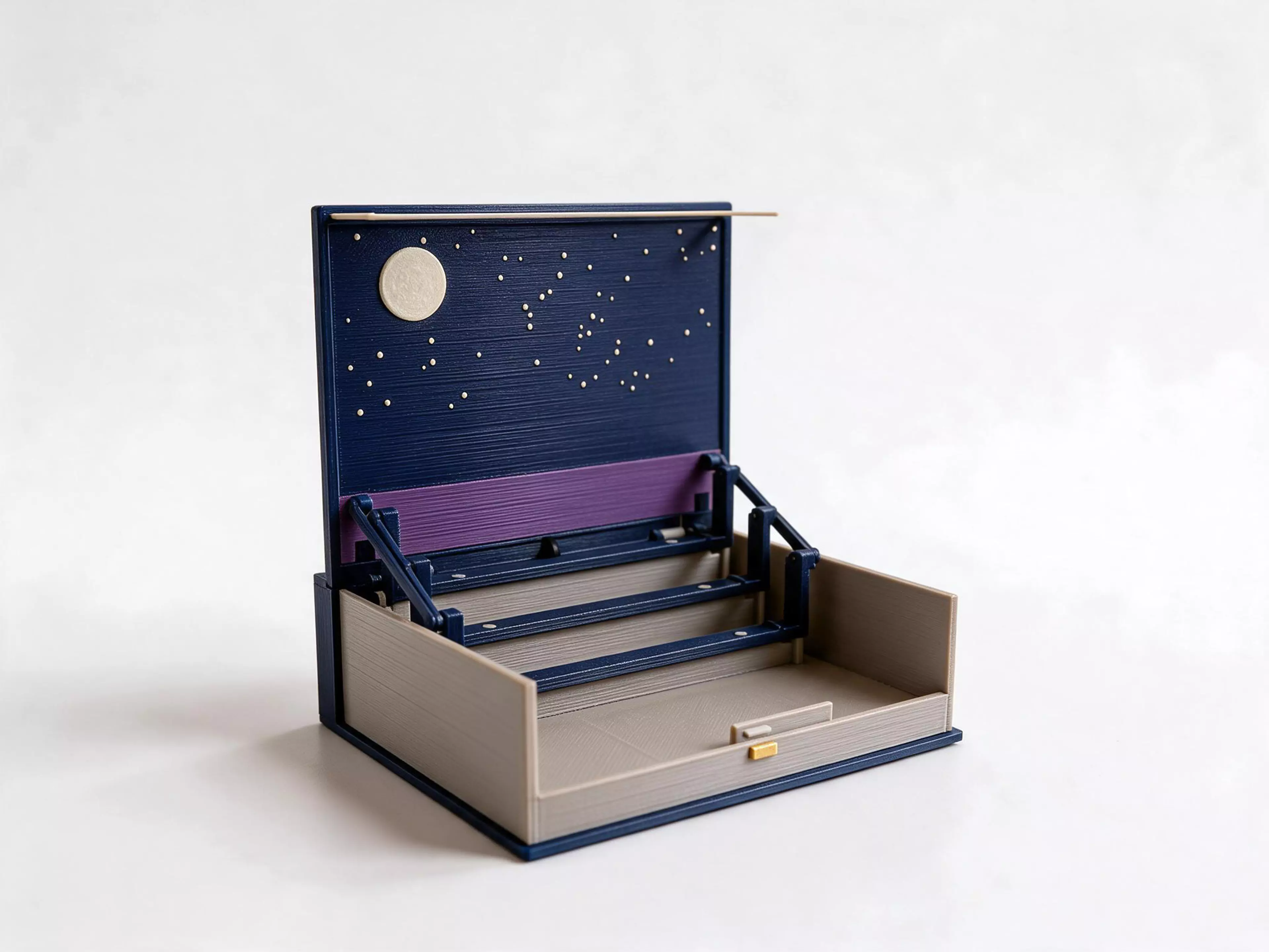 The Moonlit Atlas pop-up city book on its own. Press the brass button on the front edge and the lid lifts slowly into a night sky with a moon, a purple horizon and sixty stars, while three row frames stand up in front of it. No city comes with the book: add any Moonlit Atlas city pack (New York, London, Paris, Tokyo, San Francisco, New Orleans or Los Angeles) and its three building rows and harbour plate click onto the frames with magnets. Close the lid and the city folds flat inside. The moon and stars glow in the dark, with no batteries.