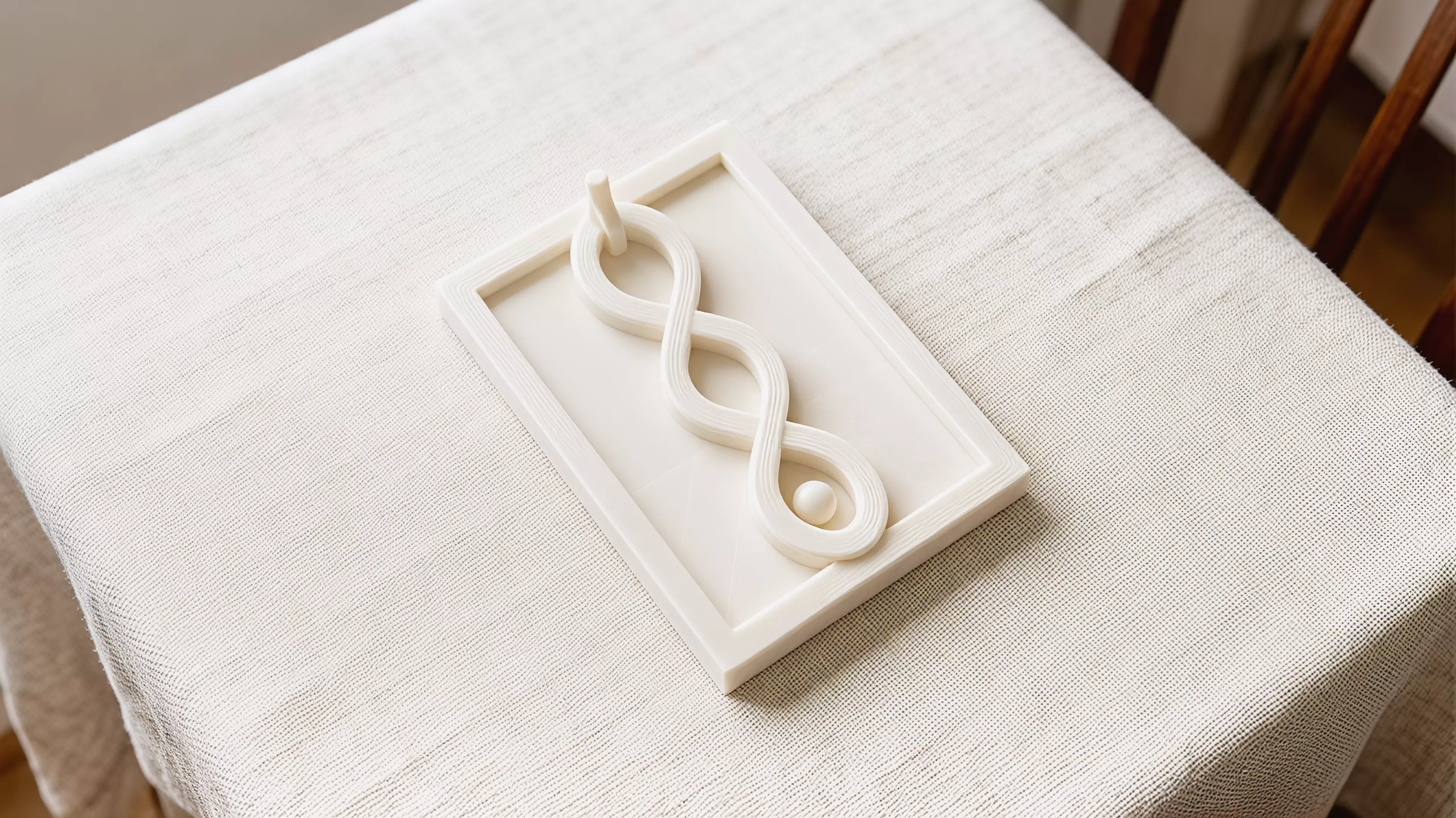 A one-handed print-in-place desk toy whose captive moon runner follows one fully visible braided figure-eight route through two separated bridges and returns home by continued thumb motion.