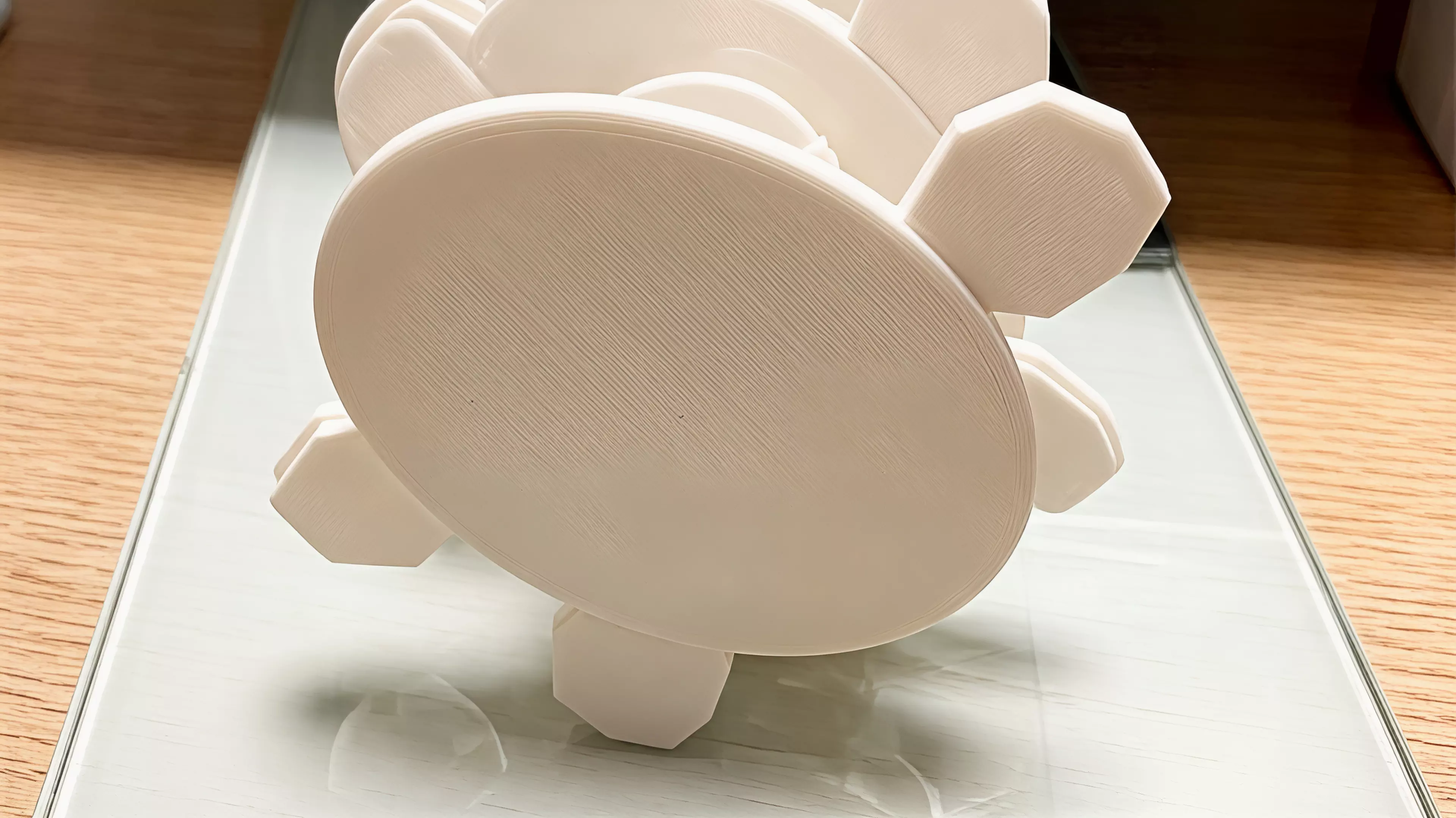 A three-part, hardware-free hand-powered desk toy: sweeping the left wing rotates the meshed pair from a low crescent form toward a moth silhouette with six star apertures.