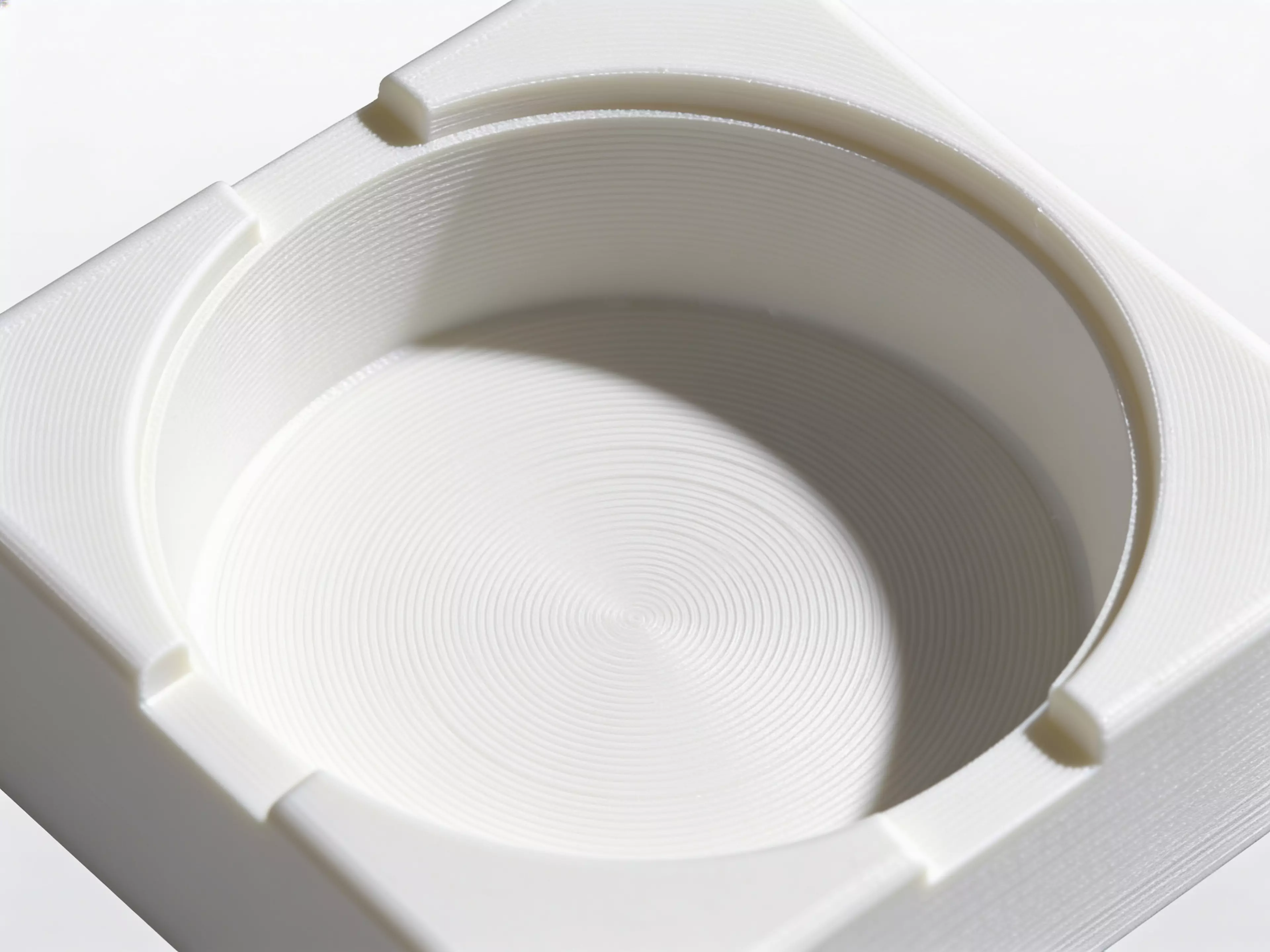 A single-piece, Scandinavian-minimal squircle stand (200 × 200 × 76 mm) that a standard 1-quart stainless bowl drops into from the top and hangs by its rolled rim on an internal support lip, with an anti-spill raised rim, two finger scallops for bowl removal, "NUNU" + paw icon raised on the front…