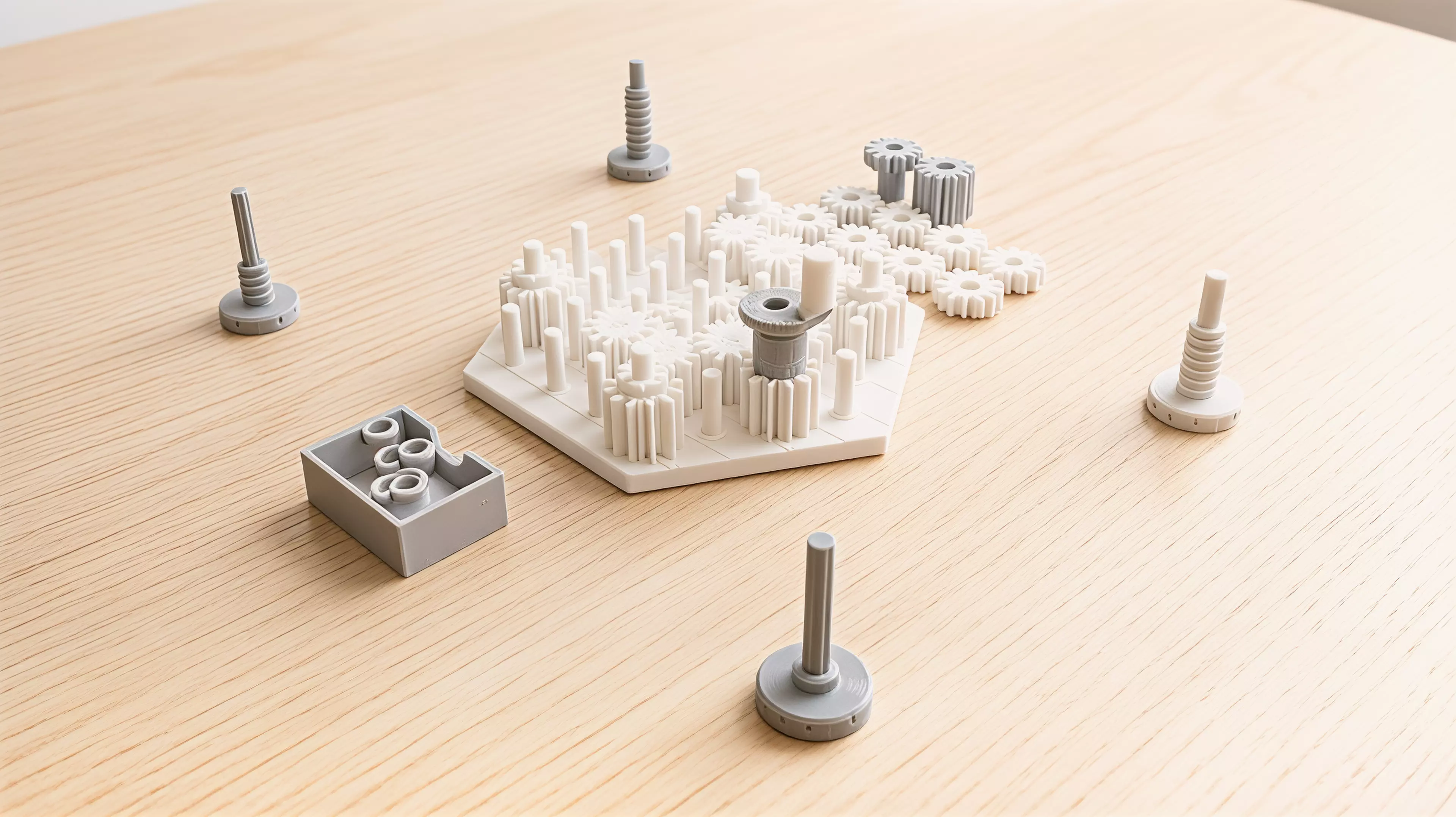 A yard of pins holds real meshing gears, and the game is played inside two facts of engineering: meshed gears turn opposite ways, and a loop with an odd number of them cannot turn at all. Each player owns one furrowed millstone gear standing on the yard's rim; a single crank gear is the only power in the box and it moves to a new rim pin at the start of every round, chosen by whoever leads that round. A turn is placing one gear — low-toothed, high-toothed, or a full-height tandem that bridges both heights — then turning the crank a quarter turn to prove you have not just bound the whole yard solid; at the end of the round the crank goes round once for real and only the mills that come up turning clockwise are grinding.

2-4 players · 35 min