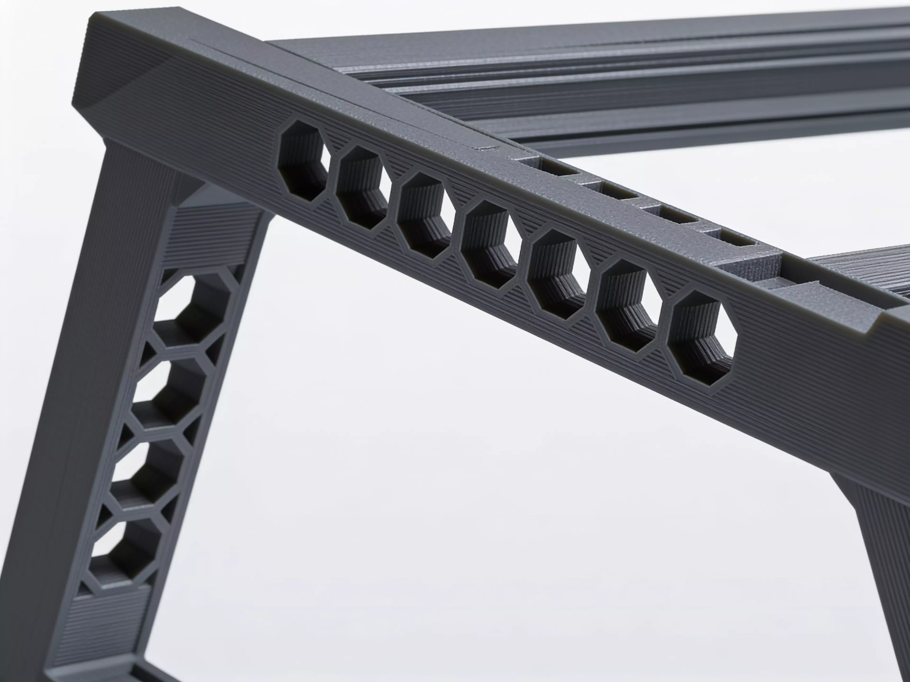 A sculpted Z-profile laptop stand designed around a 13" MacBook, tilted 22° for comfortable typing with a low-profile anti-slip ridge that catches the laptop's front edge. Two mirrored Z-legs — solid where they carry load, hex-relieved where they don't — are braced into a rigid box frame by four I-beam crossbars that press-fit straight into the legs. No screws, no heat-set inserts, no glue: just push the crossbars in and it locks together by friction alone.