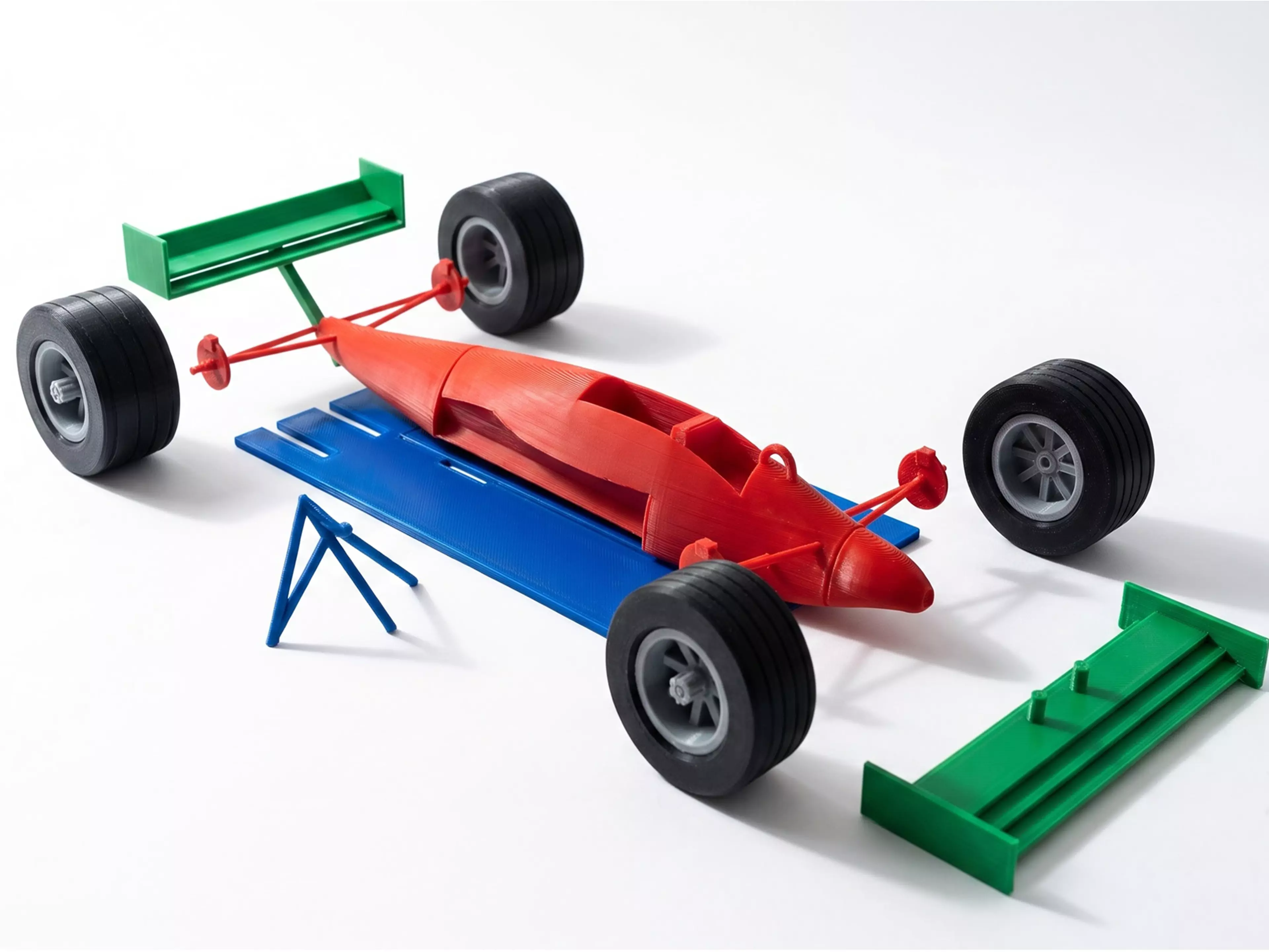 A 10-part, 17-piece 1:16 scale Mercedes-style F1 car: silver body shell (tub/nose/sidepods/engine cover with integrated suspension arms and axle stubs), black floor/diffuser, black front and rear wings, black halo, 4 rotatable wheels (2 rim + 2 tire designs, front/rear) with a center-lock retaining…