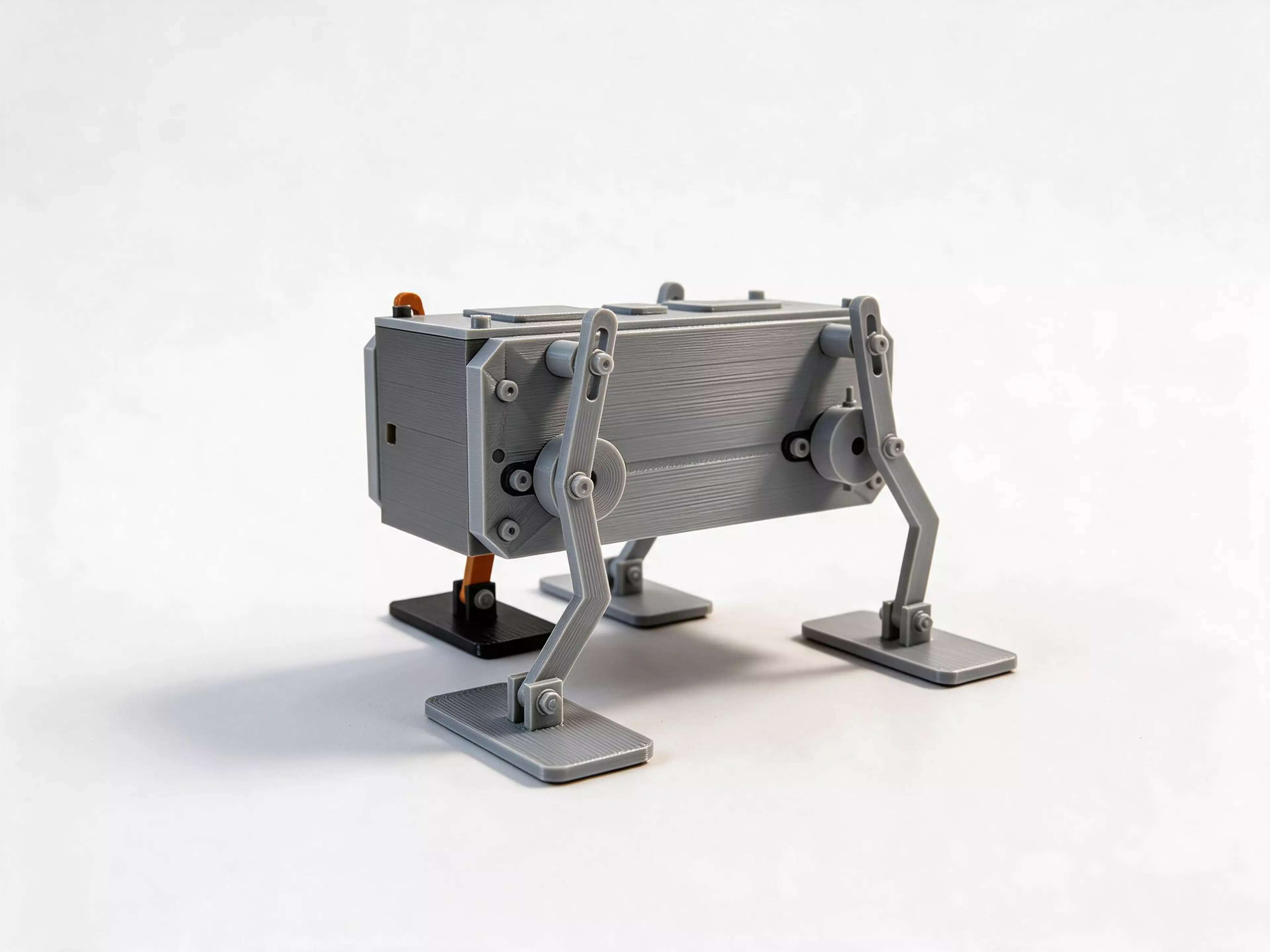 Trotter 2.0 is a wind-up quadruped. One wind of the elastic drum sends it walking on four crank-slot legs with pivoting feet, steadied by a passive rotary damper. Nine printed part types, 25 pieces, plus the listed hardware. Not yet built and tested as a physical print.