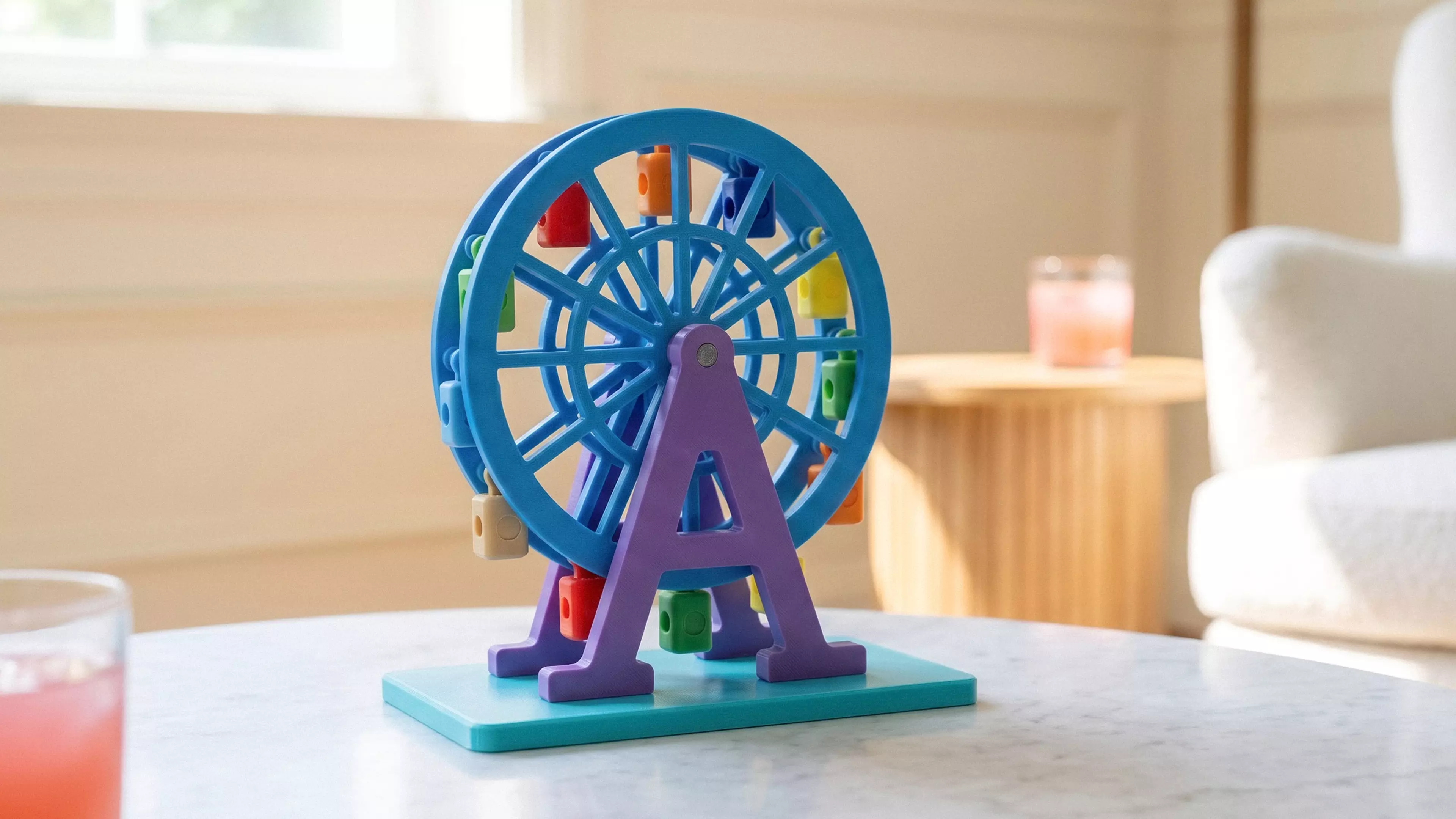 A 185 mm tall, free-spinning Ferris wheel with 12 swinging gondolas that hang upright as the wheel turns, matching the photo's A-frame support and lattice-spoke wheel, split into separately-printable parts for multi-color filament (base/towers in white, wheel rims in a sunset accent color, gondolas…