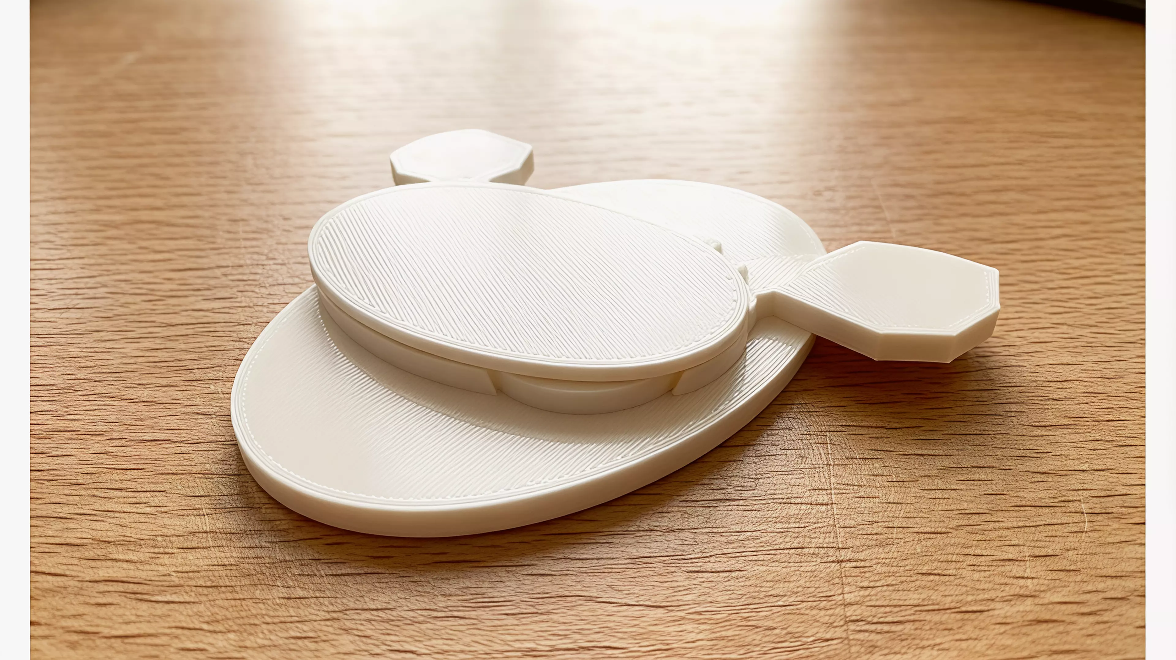 A three-part, hardware-free hand-powered desk toy: sweeping the left wing rotates the meshed pair from a low crescent form toward a moth silhouette with six star apertures.