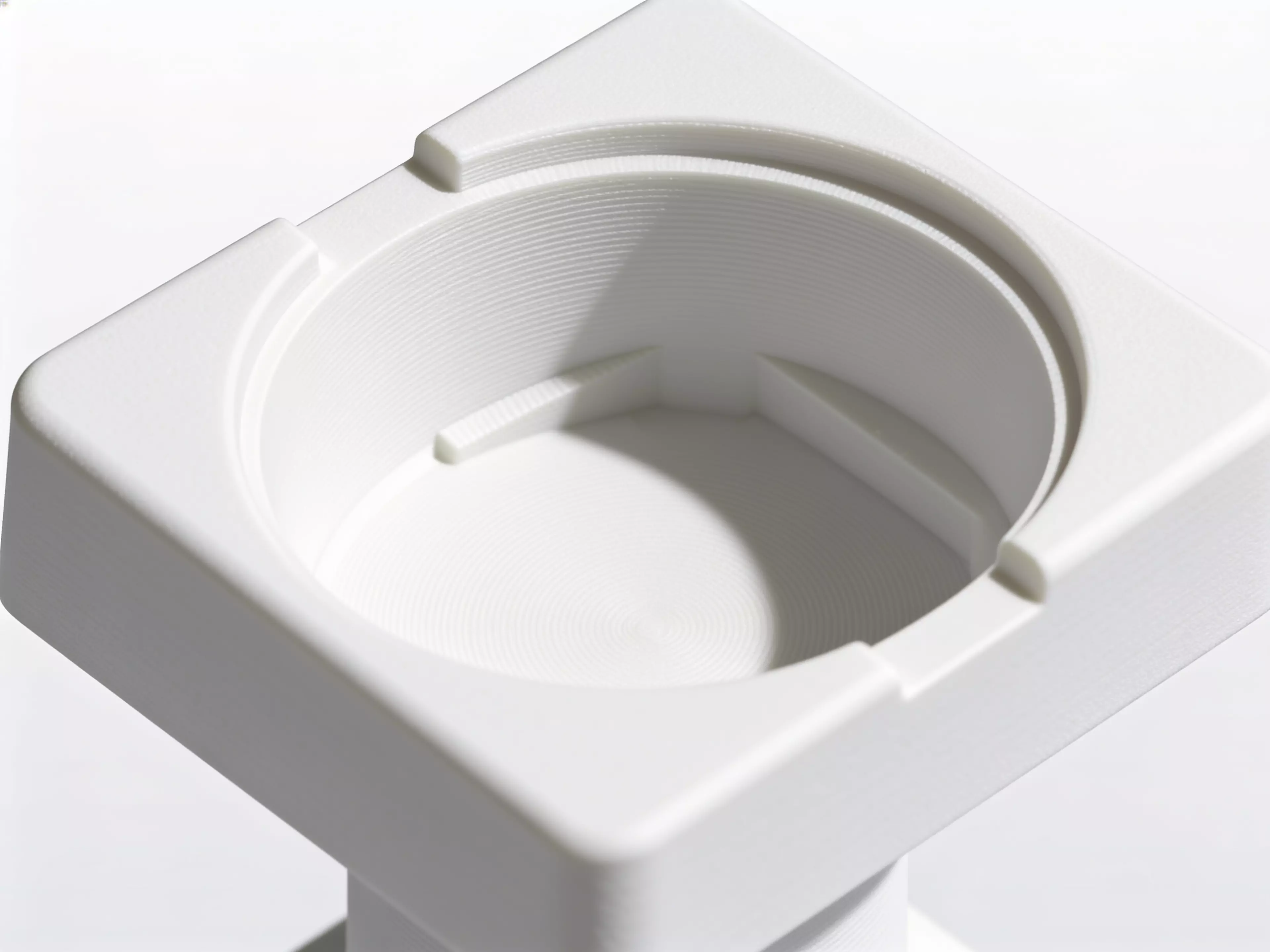 A single-piece, Scandinavian-minimal squircle stand (200 × 200 × 76 mm) that a standard 1-quart stainless bowl drops into from the top and hangs by its rolled rim on an internal support lip, with an anti-spill raised rim, two finger scallops for bowl removal, "NUNU" + paw icon raised on the front…