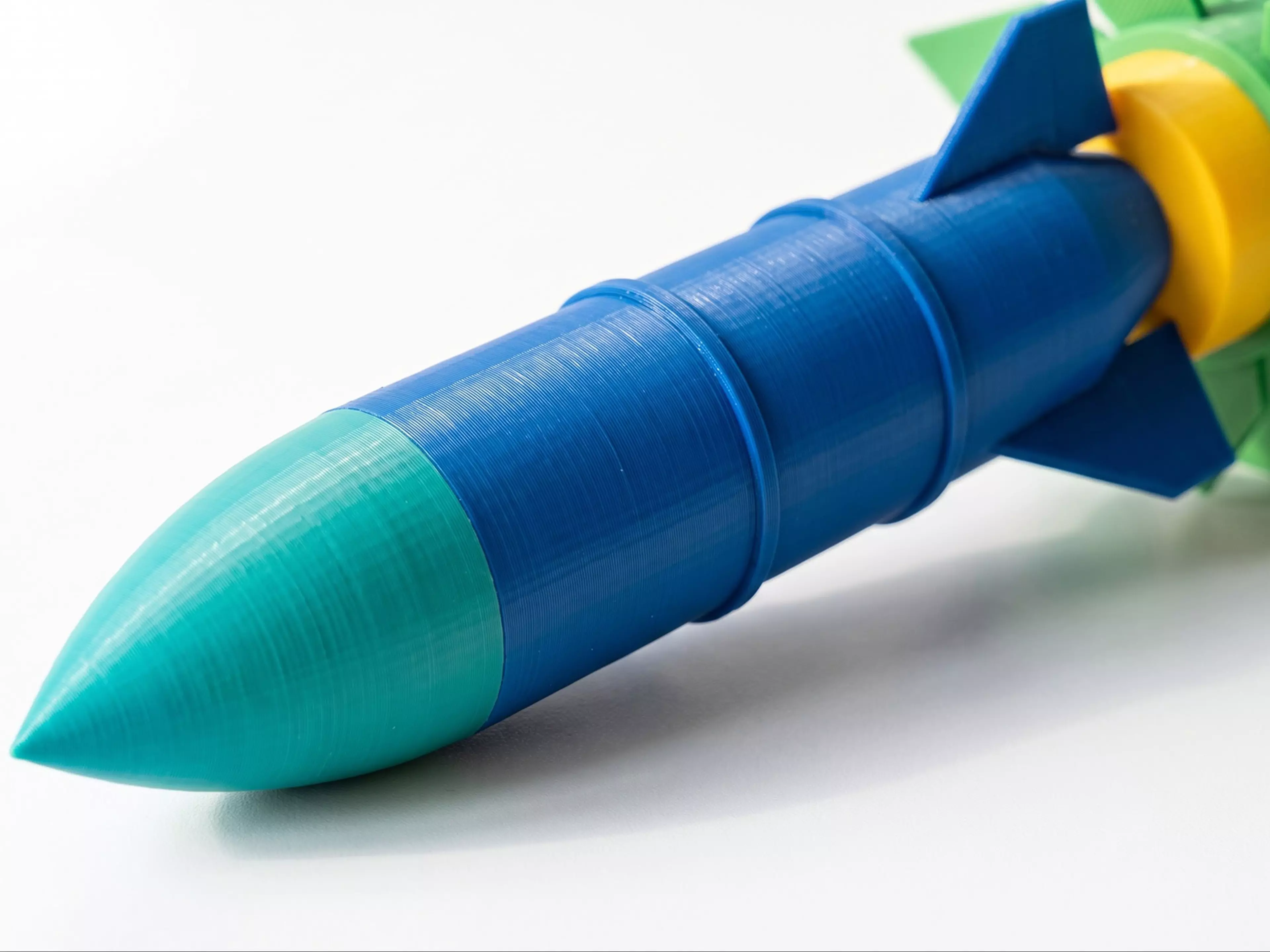 A one-of-a-kind 180 mm-tall display piece: a classic retro finned rocket that plugs into an open-bloom lotus-flower pedestal base — two separate, removable parts, each a different color.