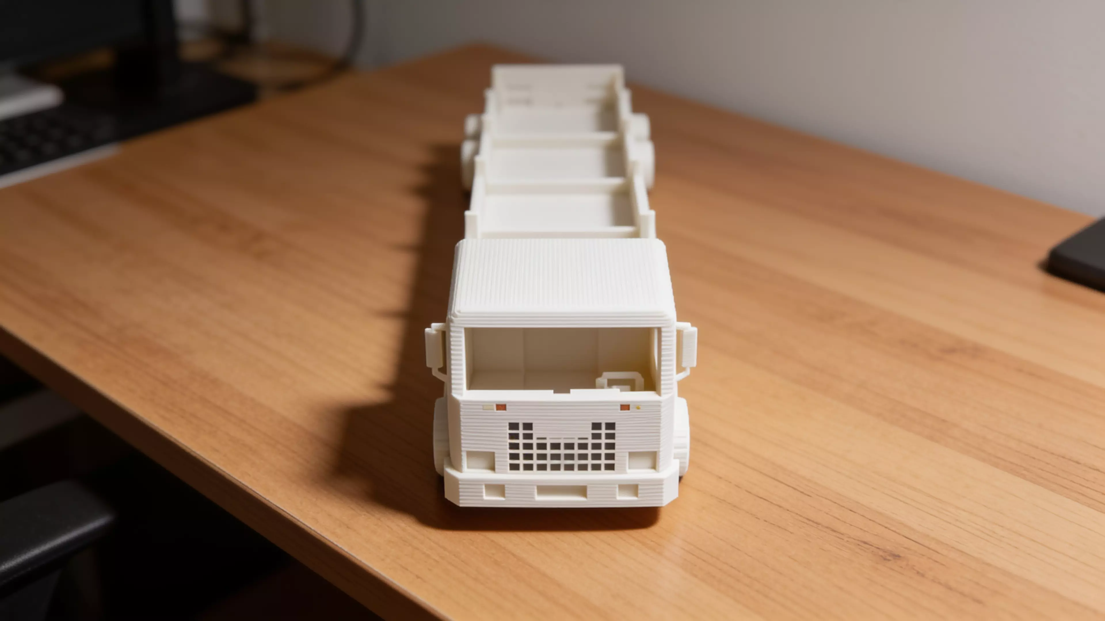 A pastel "future truck" desk shelf that carries 4 real DGX Spark units (150 × 150 × 50.5 mm) lying flat in a long row along the truck bed — built as a modular train of identical cargo bays between a cute pixel-face cab and a styled tail, on decorative six-wheel running gear.