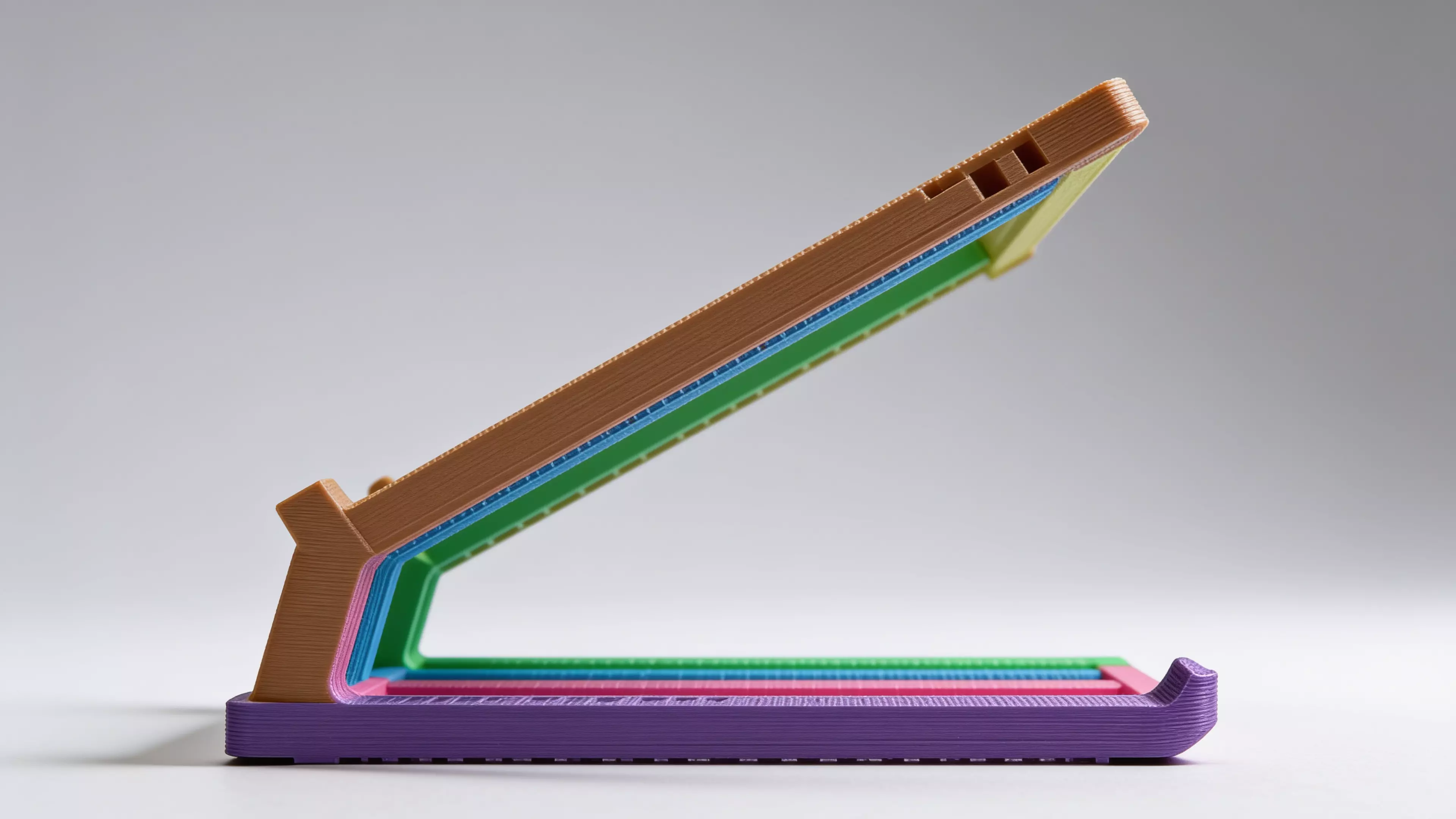 A sculpted Z-profile laptop stand designed around a 13" MacBook, tilted 22° for comfortable typing with a low-profile anti-slip ridge that catches the laptop's front edge. Two mirrored Z-legs — solid where they carry load, hex-relieved where they don't — are braced into a rigid box frame by four I-beam crossbars that press-fit straight into the legs. No screws, no heat-set inserts, no glue: just push the crossbars in and it locks together by friction alone.