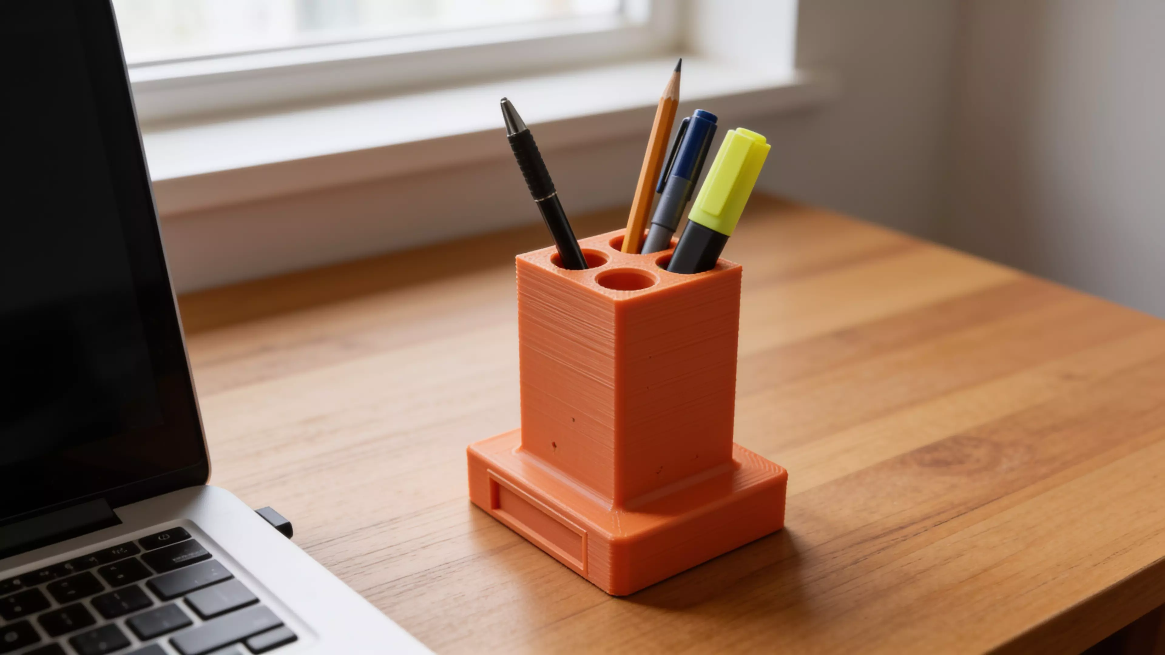 A retro-terminal desk holder: a low, wide CRT-monitor-bezel plinth (complete with a
recessed screen panel and a debossed > prompt) with an oversized rectangular
text-cursor block rising from its top like a frozen "on" blink. Five blind holes
of increasing diameter are drilled into the block's top face in a diagonal,
back-left-to-front-right layout, each sized and chamfered for a specific
implement — stylus, pen, pencil, marker, highlighter. Single piece, flat-bed
print, no supports.