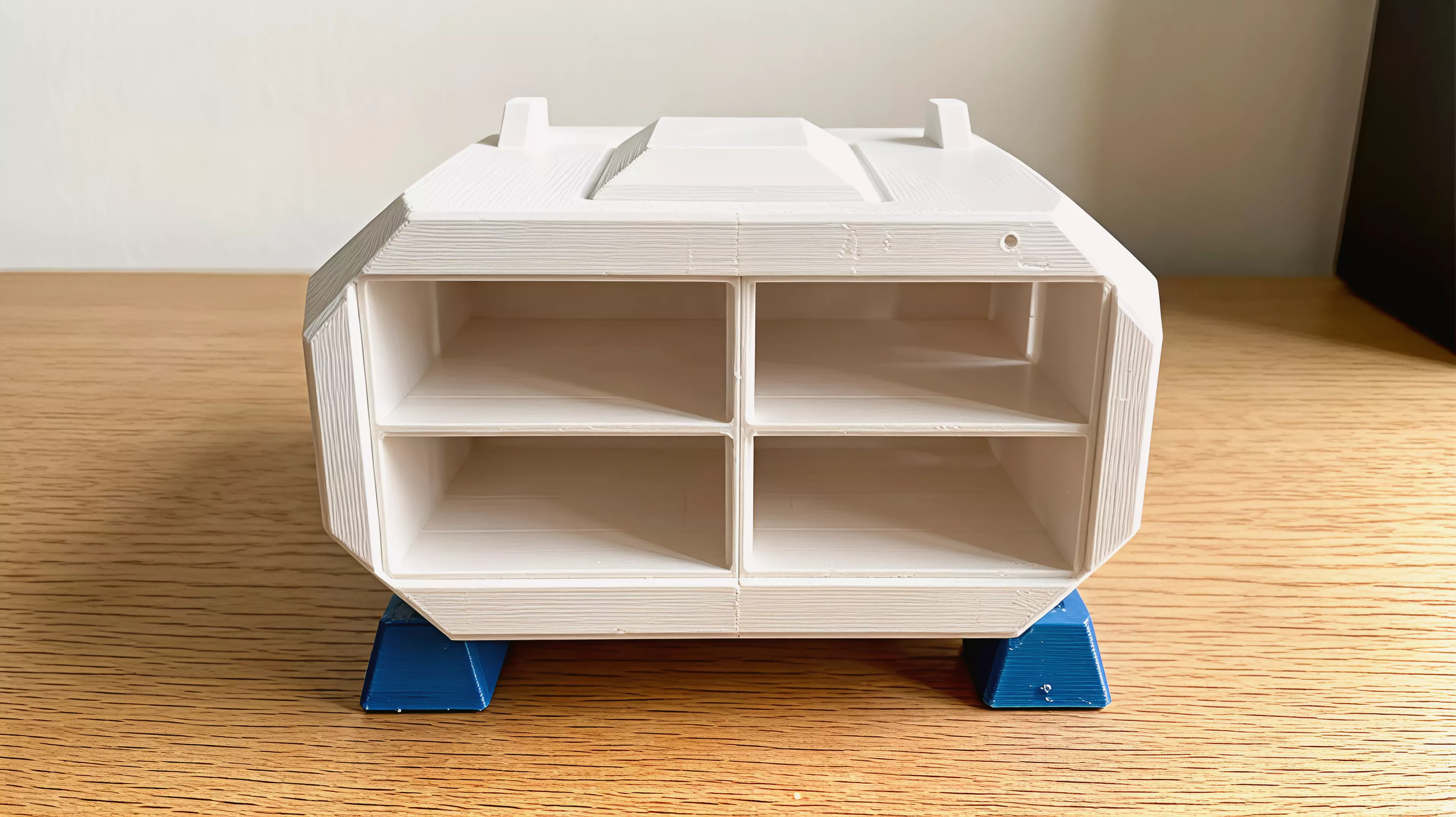 A knock-down sci-fi shuttle enclosure holding 4× NVIDIA DGX Spark in a 2×2 open-ended tunnel grid: two mirror shell halves (split on the central vertical plane), a dark-grey cockpit canopy, two swept blade fins, and four dark-grey landing feet — all M3/dowel assembled, printed without supports.