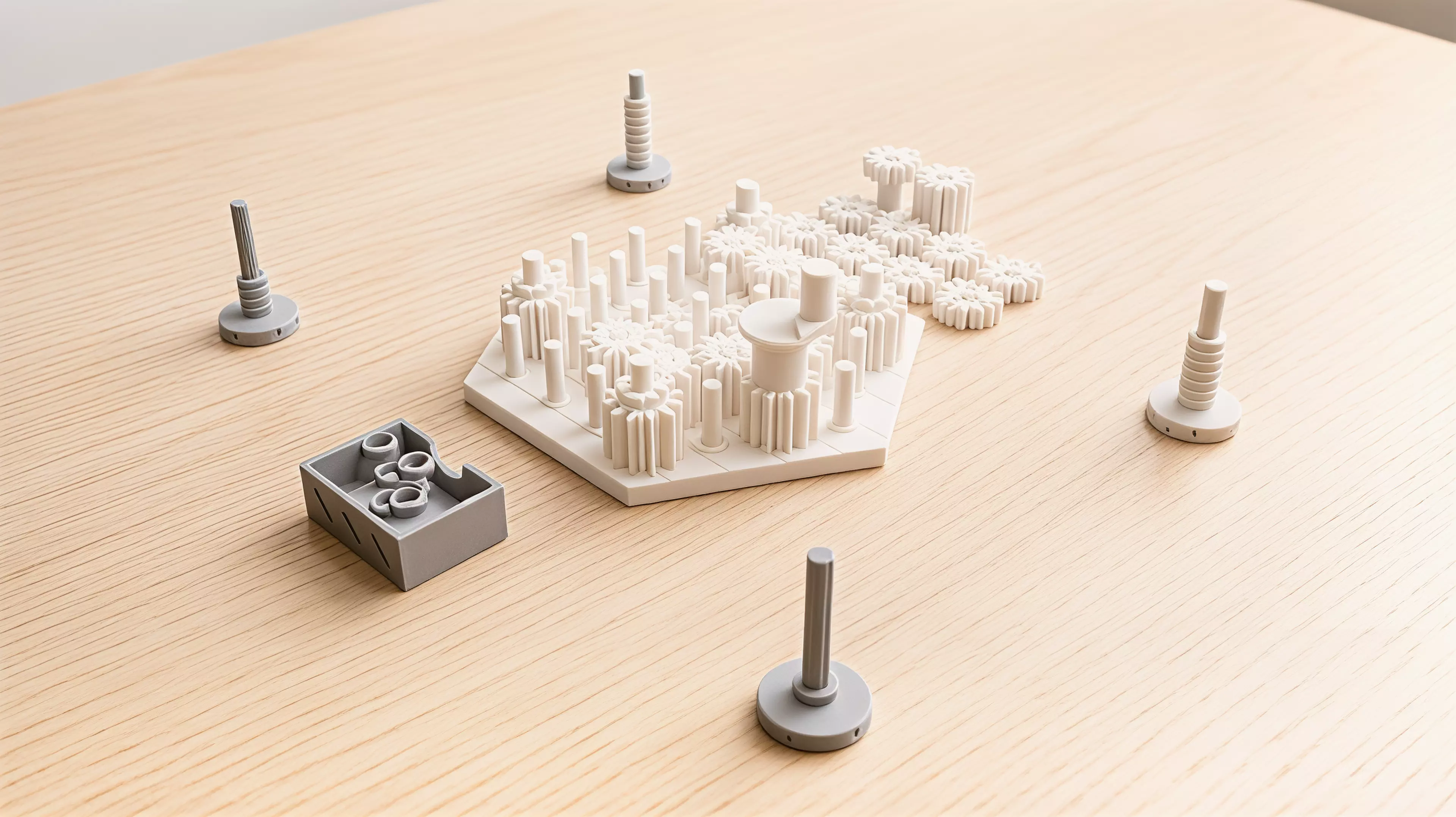 A yard of pins holds real meshing gears, and the game is played inside two facts of engineering: meshed gears turn opposite ways, and a loop with an odd number of them cannot turn at all. Each player owns one furrowed millstone gear standing on the yard's rim; a single crank gear is the only power in the box and it moves to a new rim pin at the start of every round, chosen by whoever leads that round. A turn is placing one gear — low-toothed, high-toothed, or a full-height tandem that bridges both heights — then turning the crank a quarter turn to prove you have not just bound the whole yard solid; at the end of the round the crank goes round once for real and only the mills that come up turning clockwise are grinding.

2-4 players · 35 min