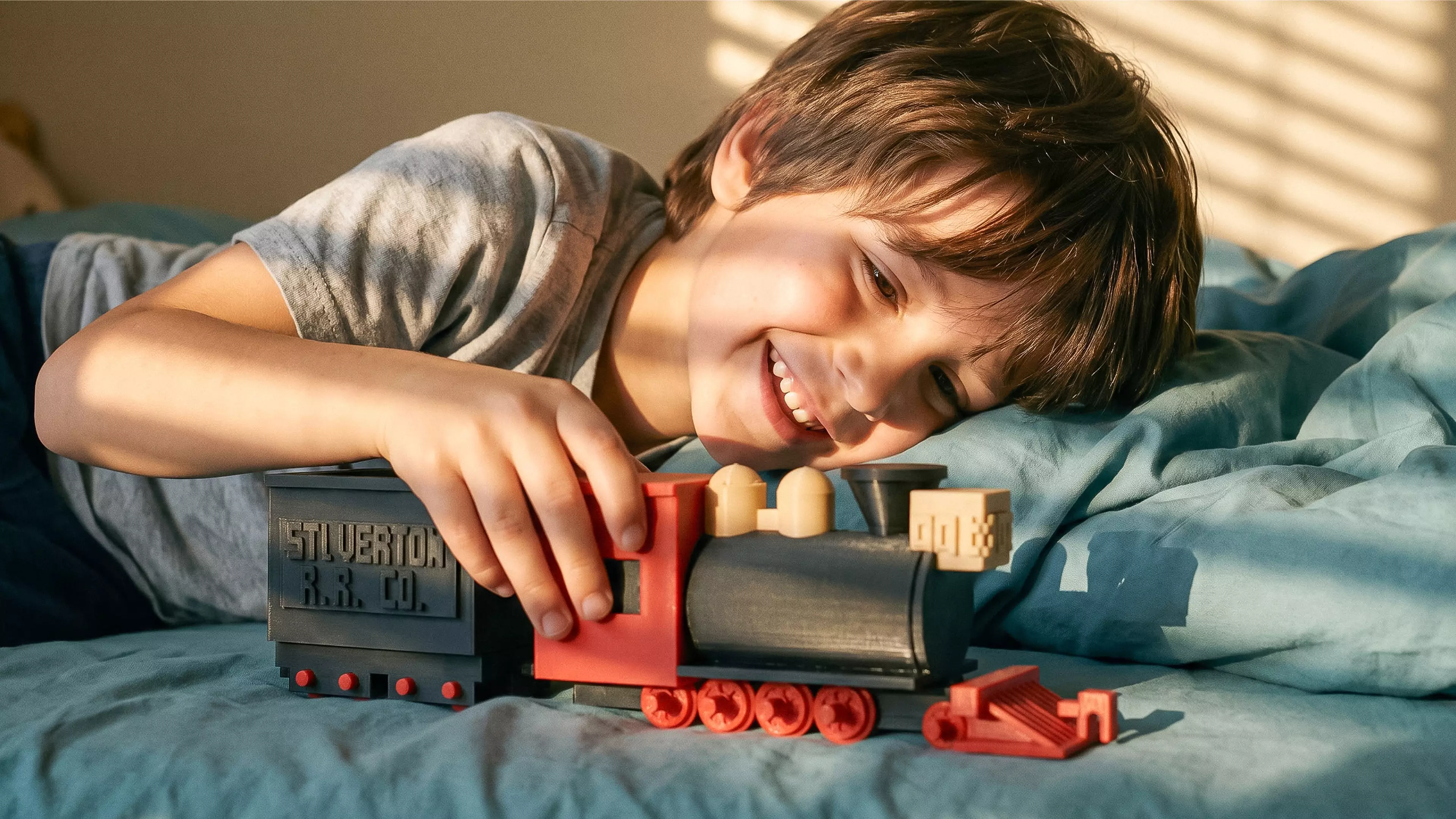 A 1:87 buildable desk model of Silverton Railroad No. 100, with a four-driver 2-8-0 profile, separate rolling wheelsets, a two-truck tender, and a hook-and-bar coupling.