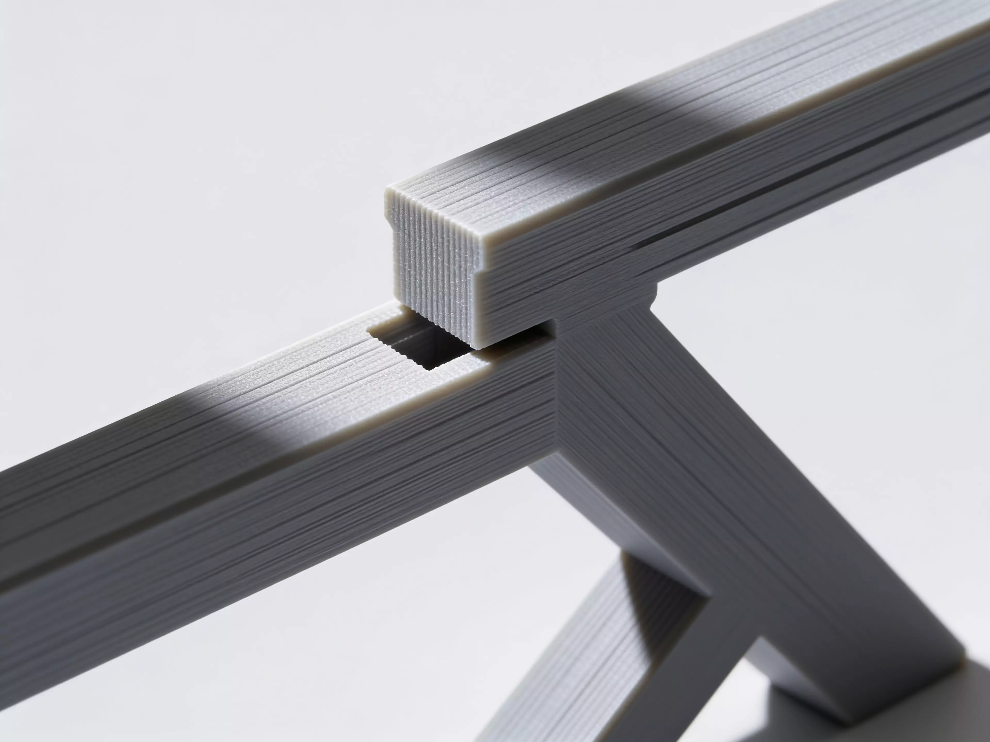 A sculpted Z-profile laptop stand designed around a 13" MacBook, tilted 22° for comfortable typing with a low-profile anti-slip ridge that catches the laptop's front edge. Two mirrored Z-legs — solid where they carry load, hex-relieved where they don't — are braced into a rigid box frame by four I-beam crossbars that press-fit straight into the legs. No screws, no heat-set inserts, no glue: just push the crossbars in and it locks together by friction alone.