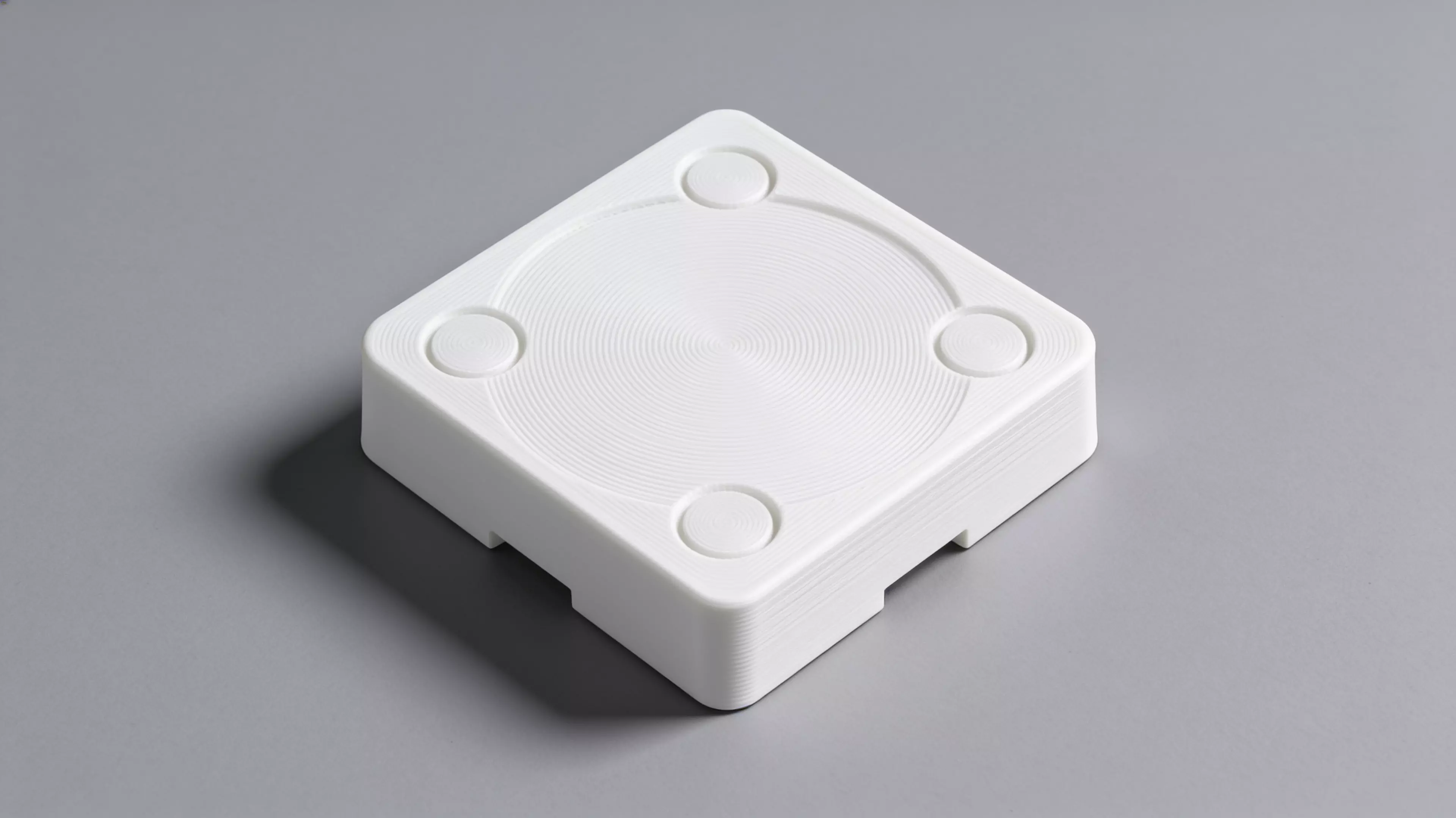 A single-piece, Scandinavian-minimal squircle stand (200 × 200 × 76 mm) that a standard 1-quart stainless bowl drops into from the top and hangs by its rolled rim on an internal support lip, with an anti-spill raised rim, two finger scallops for bowl removal, "NUNU" + paw icon raised on the front…