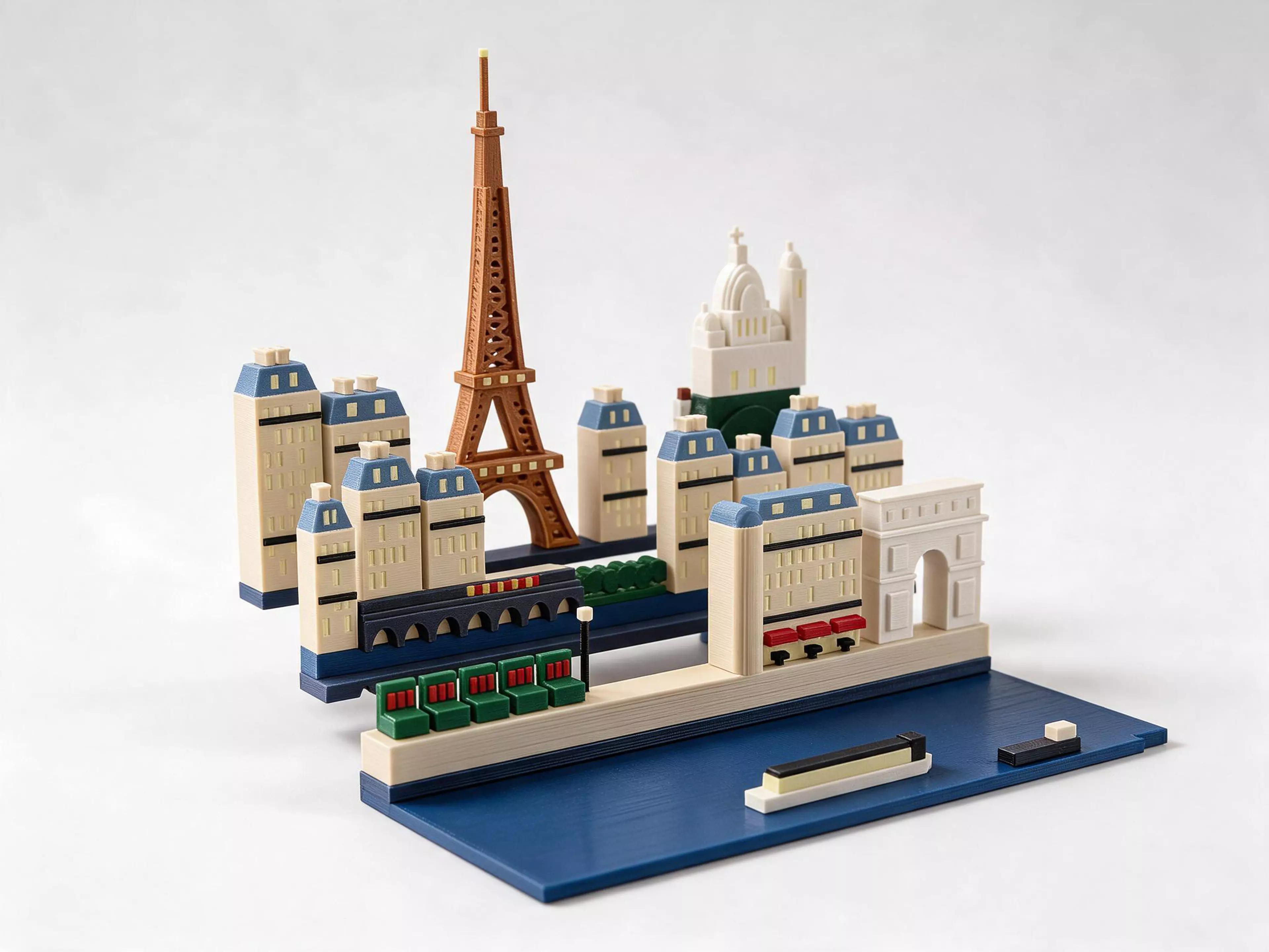 A Paris set for the Moonlit Atlas pop-up book: three rows of miniature buildings and a harbour plate that click onto the book's row frames with magnets. In this set: the Eiffel Tower in an open lattice, Sacré-Cœur with its painter, the Arc de Triomphe, a corner café with Haussmann balconies, the bouquinistes' green boxes on the quay, and a bateau-mouche on the Seine. Windows and stars glow in the dark, with no batteries. It needs the Moonlit Atlas book, which is sold separately and comes with New York, and it swaps with any other city set in seconds.