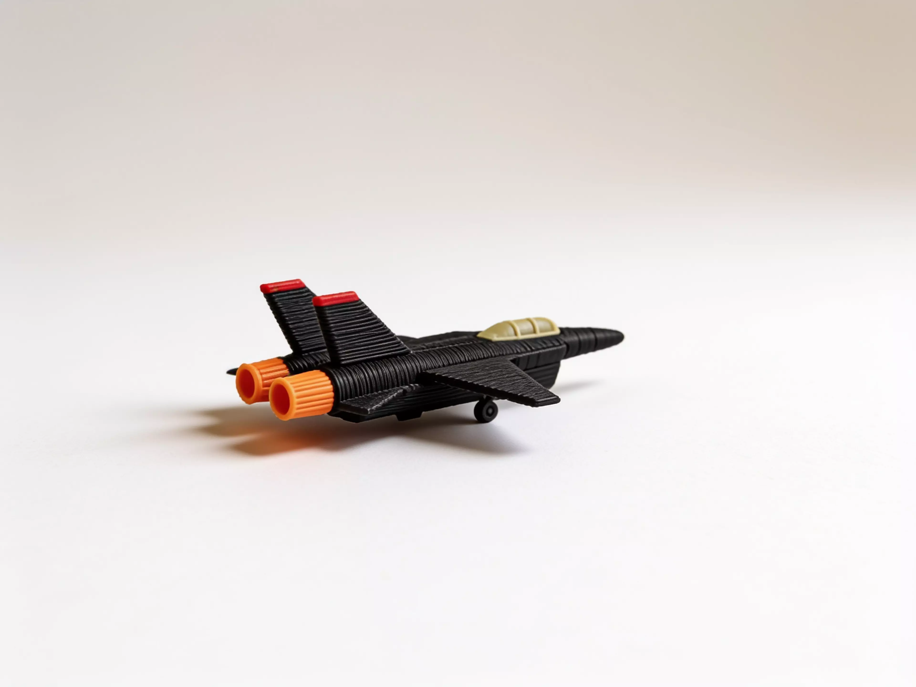 A 390 mm-wingspan F-14D Tomcat that sits on its own landing gear like a ramp-parked jet. Sixteen colour-separated printed parts - gloss-black airframe and spine deck, pale-khaki tandem canopy, red-tipped twin tails, red intake frames and nose strut, orange afterburner nozzles and a full tricycle gear - assemble into a spread-wing display pose. 390 x 388 x 117 mm (about 15.4 x 15.3 x 4.6 in).