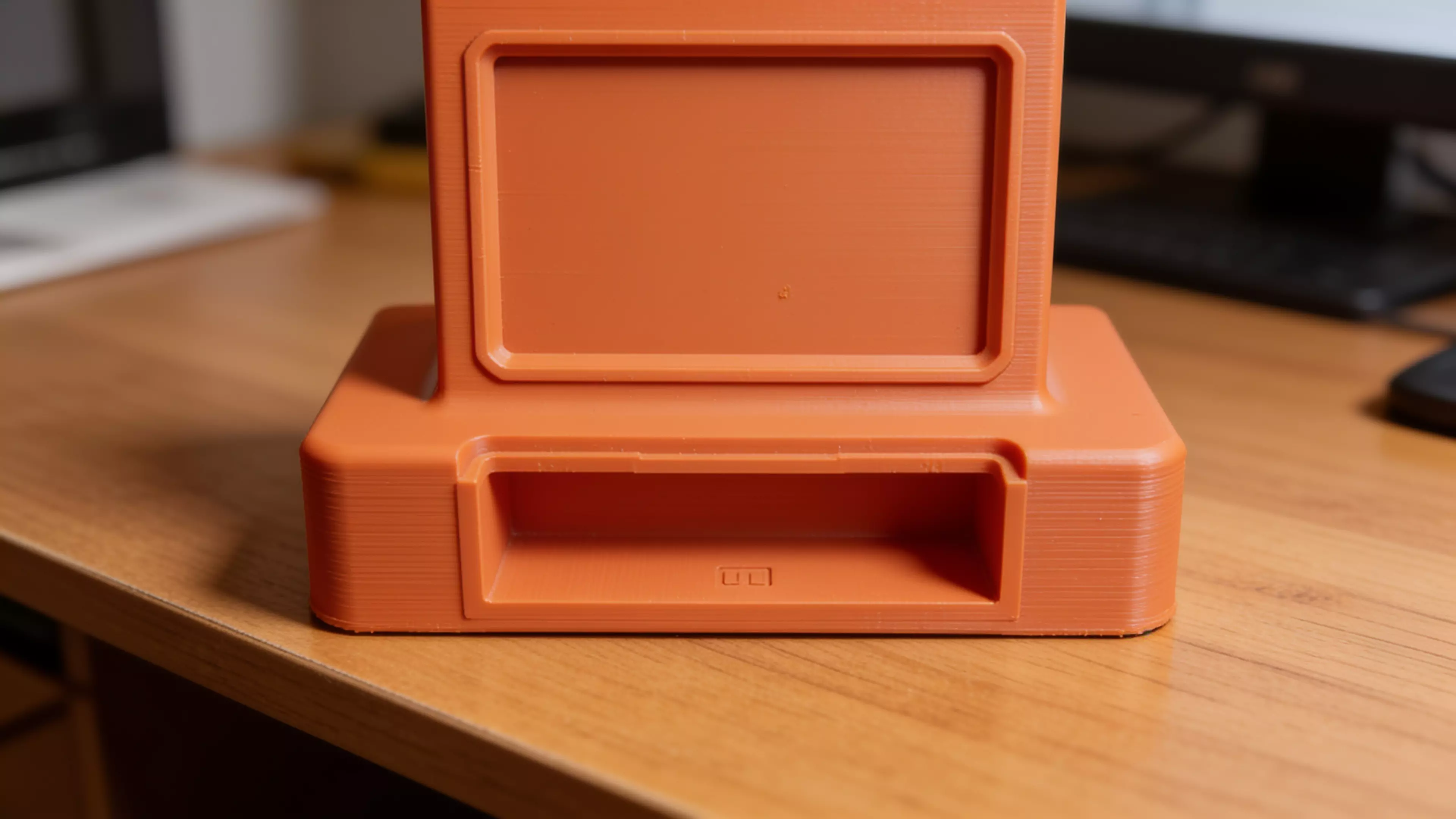 A retro-terminal desk holder: a low, wide CRT-monitor-bezel plinth (complete with a
recessed screen panel and a debossed > prompt) with an oversized rectangular
text-cursor block rising from its top like a frozen "on" blink. Five blind holes
of increasing diameter are drilled into the block's top face in a diagonal,
back-left-to-front-right layout, each sized and chamfered for a specific
implement — stylus, pen, pencil, marker, highlighter. Single piece, flat-bed
print, no supports.