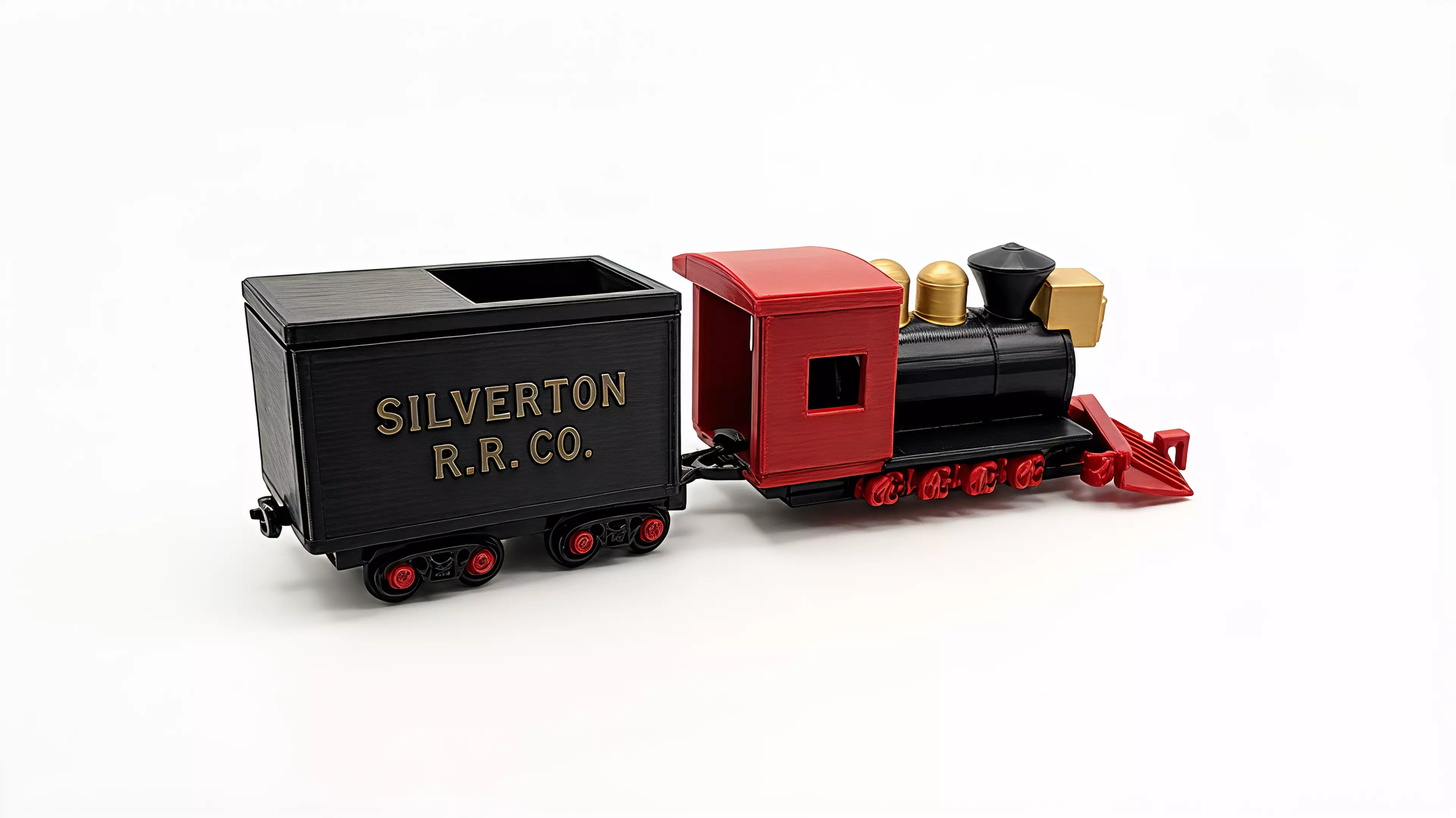 A 1:87 buildable desk model of Silverton Railroad No. 100, with a four-driver 2-8-0 profile, separate rolling wheelsets, a two-truck tender, and a hook-and-bar coupling.