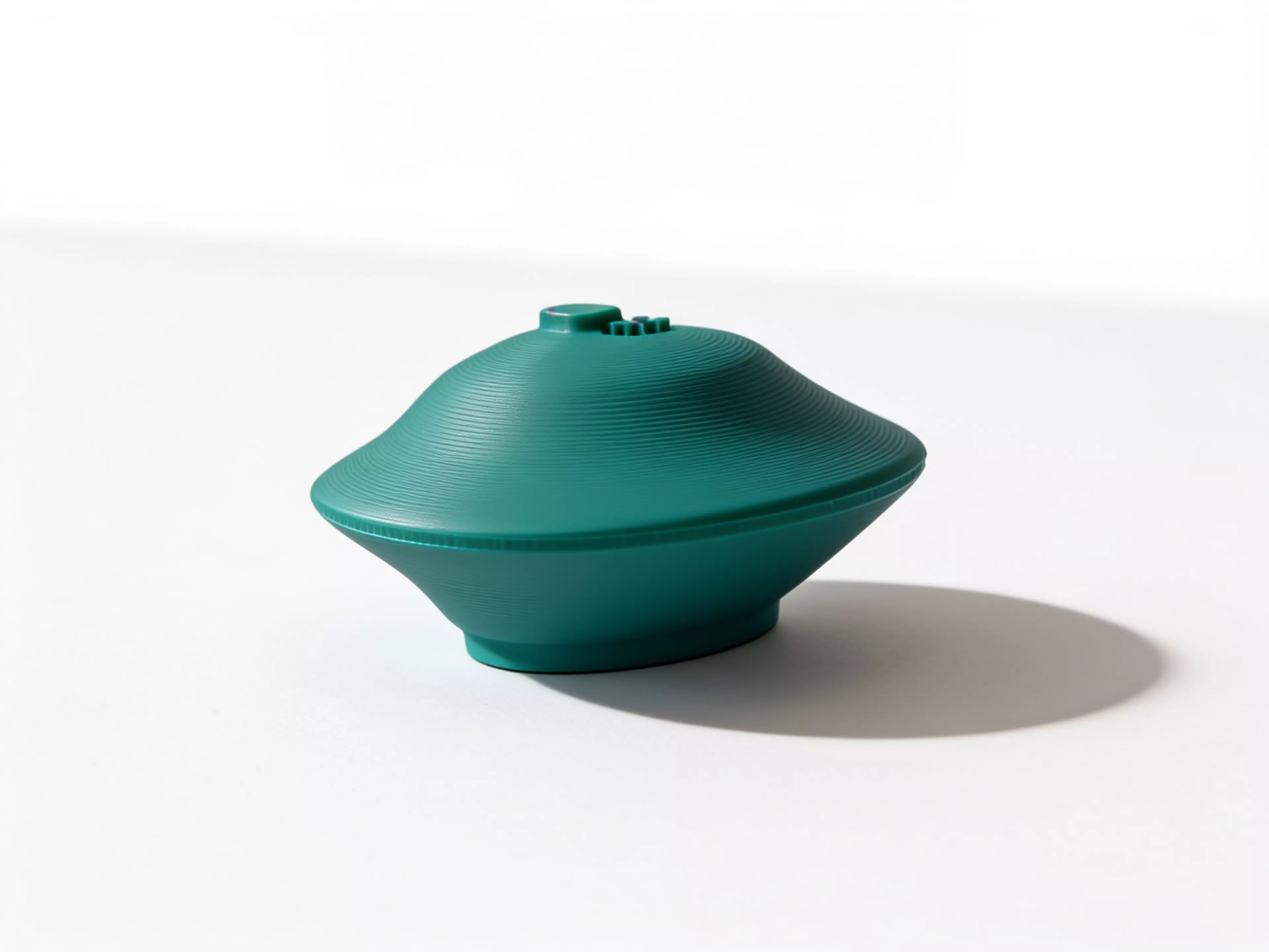 A palm-size one-piece desk wobbler designed for a sideways flick or gentle roll, with a raised smiling-star home cue.