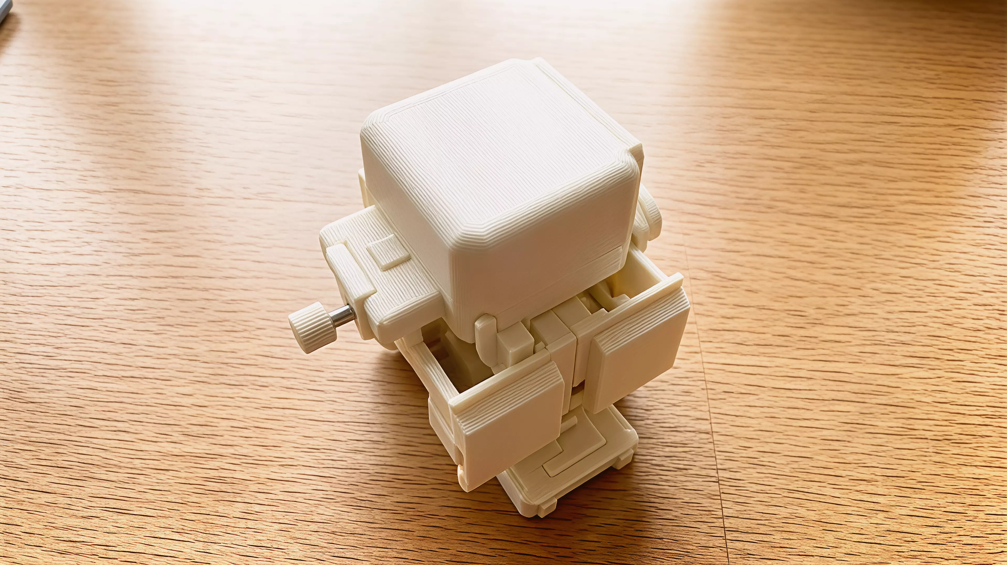 An original palm-size all-printed duck-like desk automaton designed around a visible ring crank, eccentric cam, paired-hip waddle, opening clip beak, rocking belly, keyed eyes, and removable captive-roller skates.