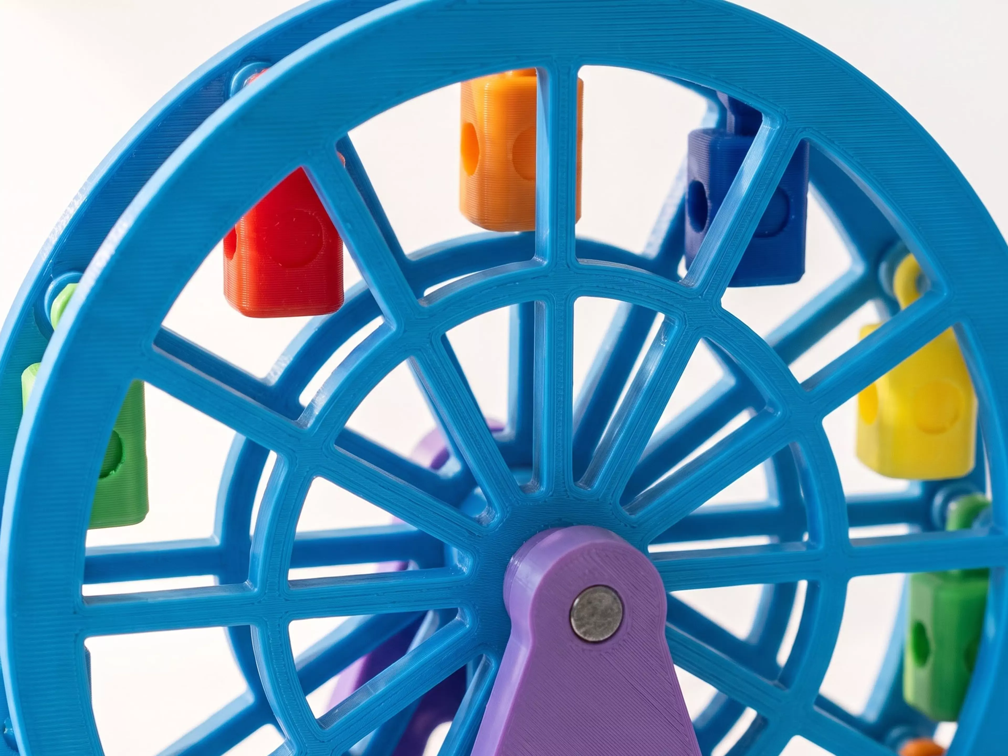 A 185 mm tall, free-spinning Ferris wheel with 12 swinging gondolas that hang upright as the wheel turns, matching the photo's A-frame support and lattice-spoke wheel, split into separately-printable parts for multi-color filament (base/towers in white, wheel rims in a sunset accent color, gondolas…