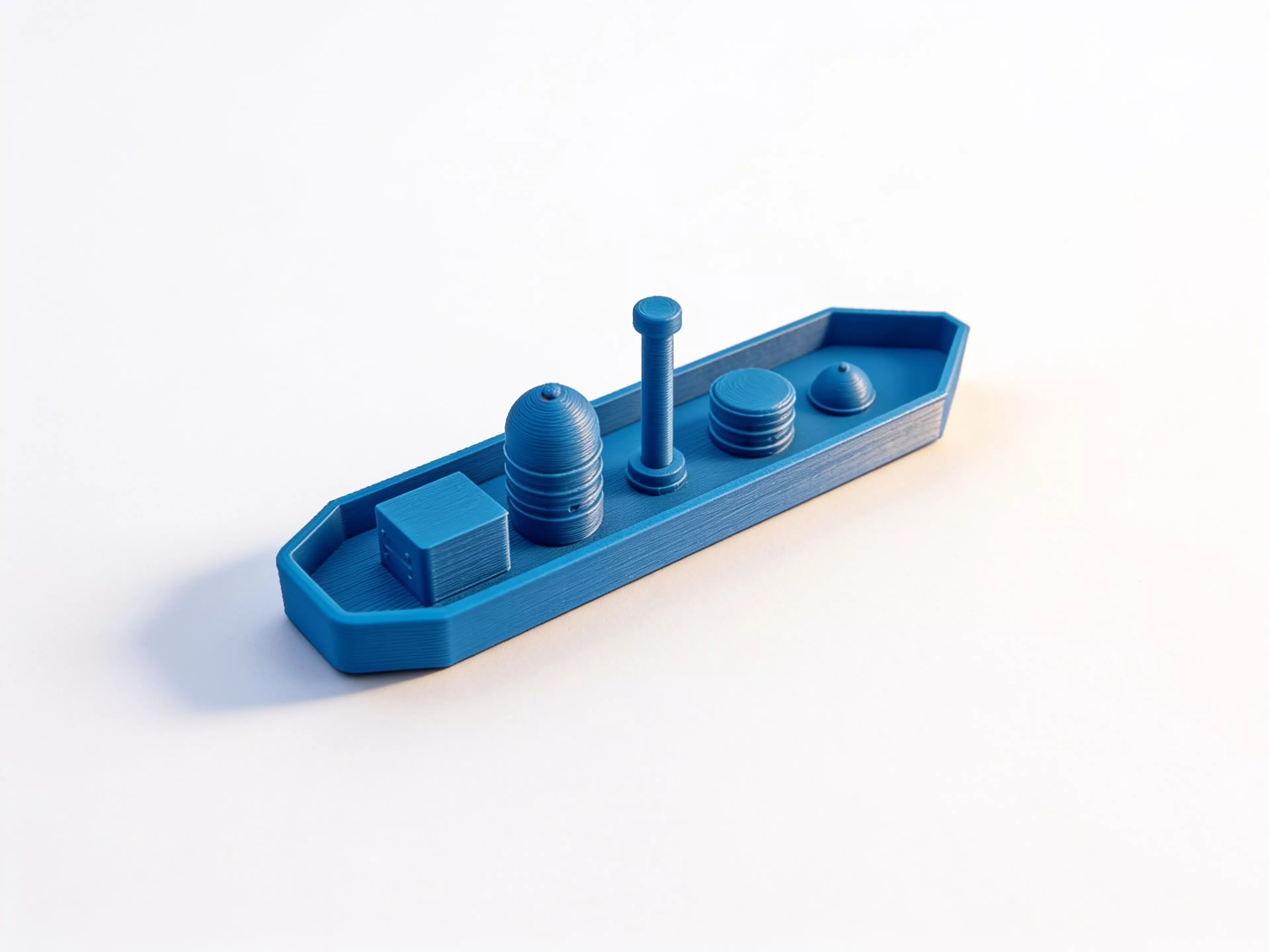 A 6-part toy cargo barge: one hull plus five separate deck-cargo pieces (crate, tall tank/silo, mast, drum, dome hatch) that peg into locating bosses on the deck, in a rugged industrial-workboat style (rivets, ribbed banding, hard chamfered hull corners).