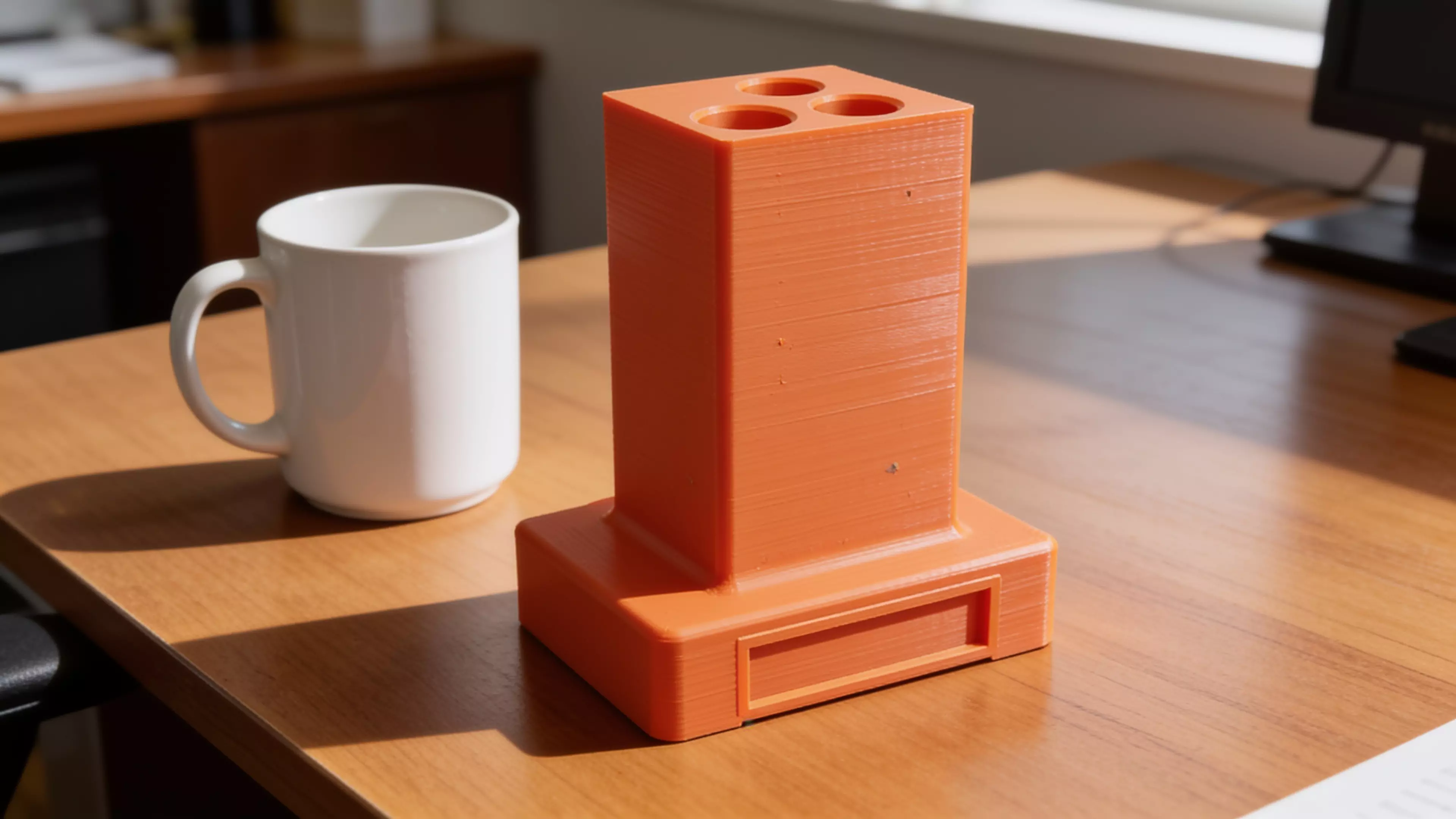 A retro-terminal desk holder: a low, wide CRT-monitor-bezel plinth (complete with a
recessed screen panel and a debossed > prompt) with an oversized rectangular
text-cursor block rising from its top like a frozen "on" blink. Five blind holes
of increasing diameter are drilled into the block's top face in a diagonal,
back-left-to-front-right layout, each sized and chamfered for a specific
implement — stylus, pen, pencil, marker, highlighter. Single piece, flat-bed
print, no supports.