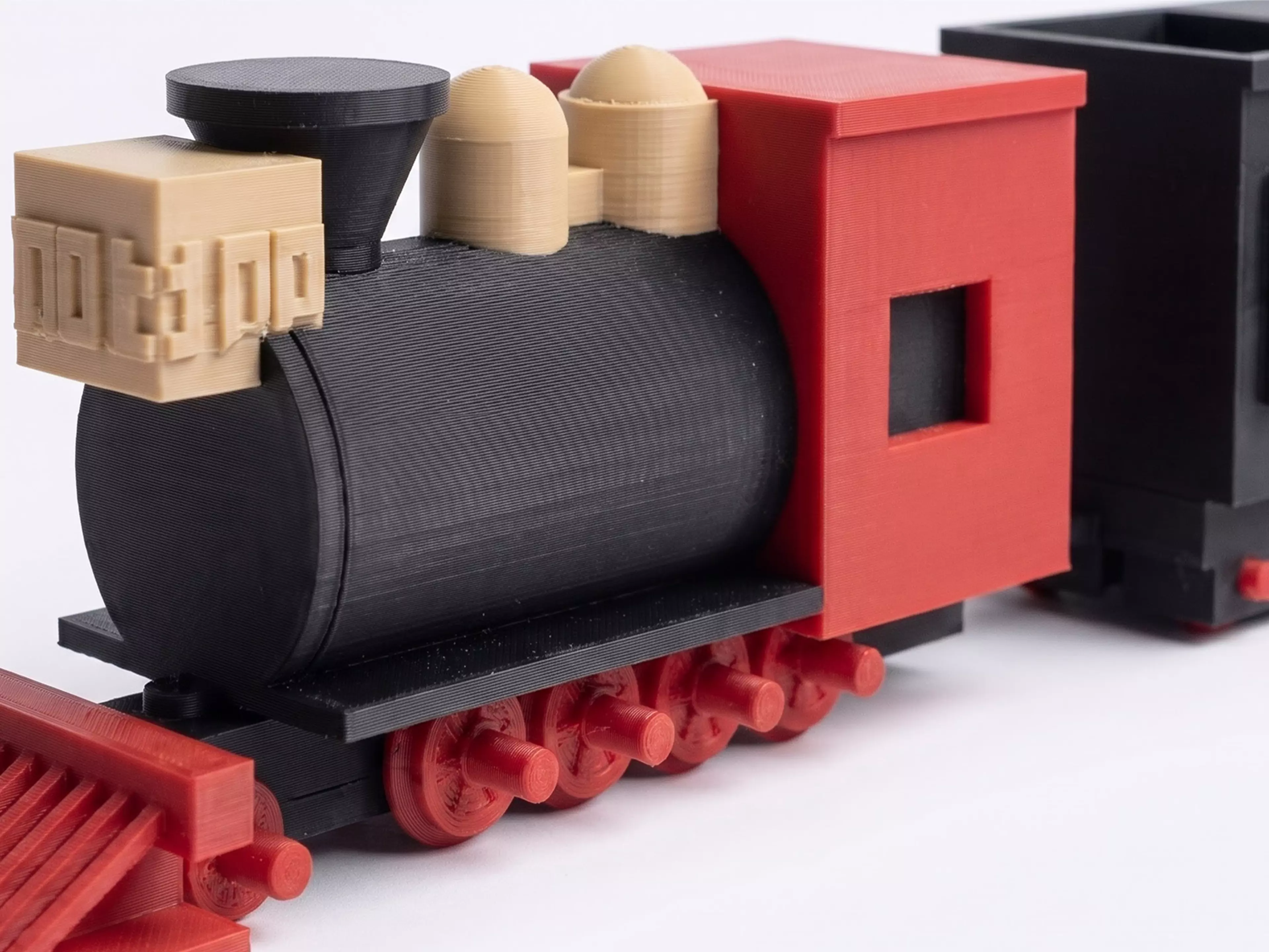 A 1:87 buildable desk model of Silverton Railroad No. 100, with a four-driver 2-8-0 profile, separate rolling wheelsets, a two-truck tender, and a hook-and-bar coupling.